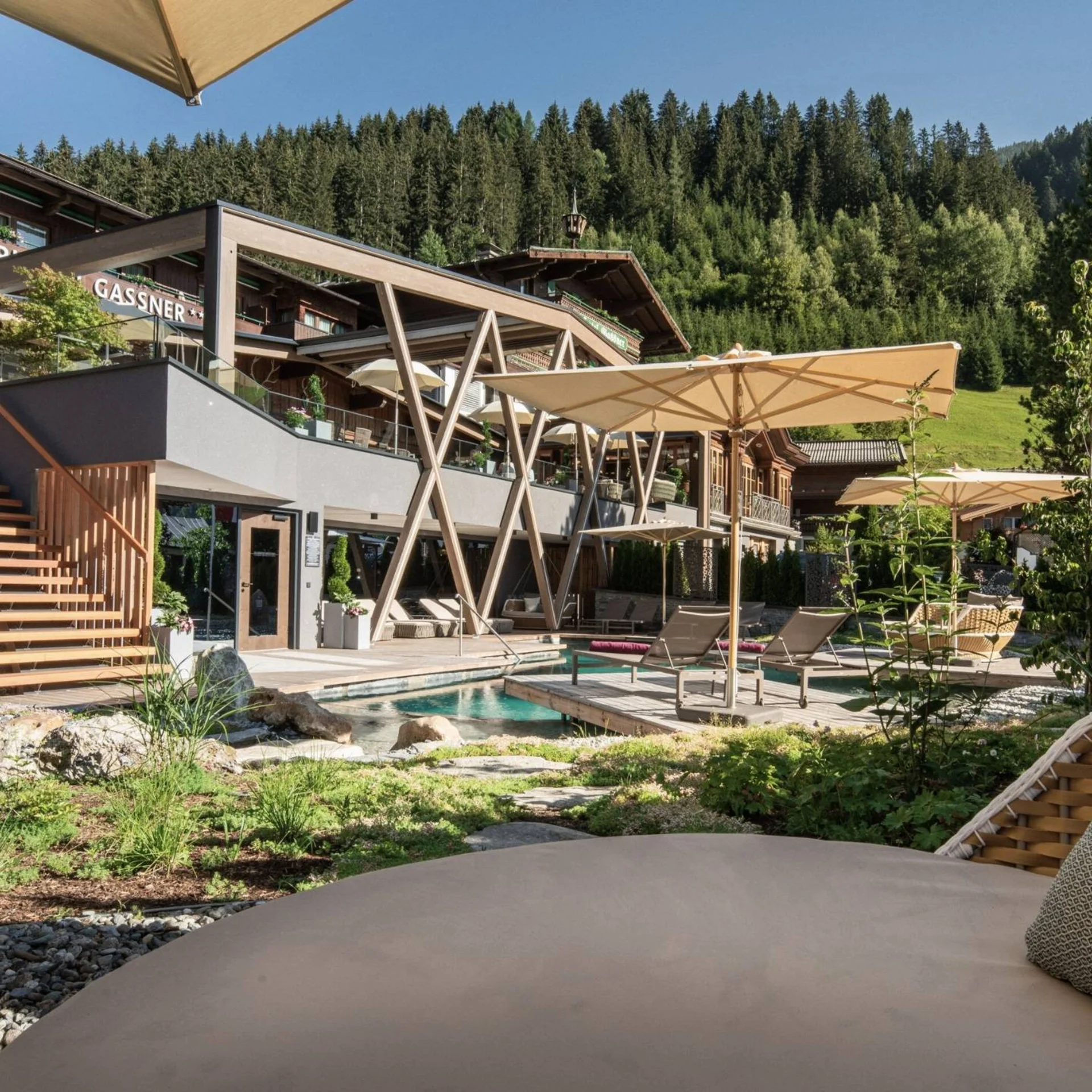 Home Außenbereich eines Hotels mit Pool, Sonnenschirmen und Bergen im Hintergrund