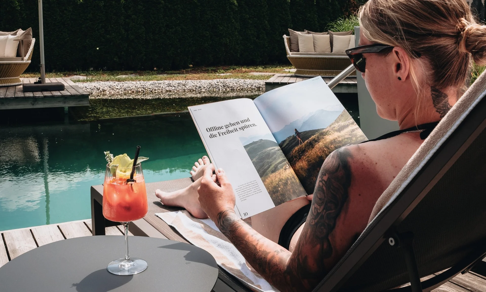 Home Person liest Buch und entspannt am Wasser mit Cocktail auf Tisch