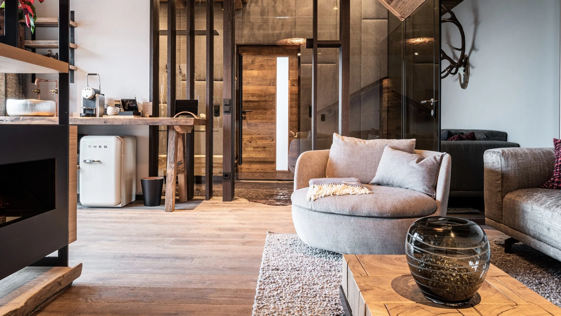 Baumhaus Moderner Wohnbereich mit grauem Sessel, Glasvase und Holzboden