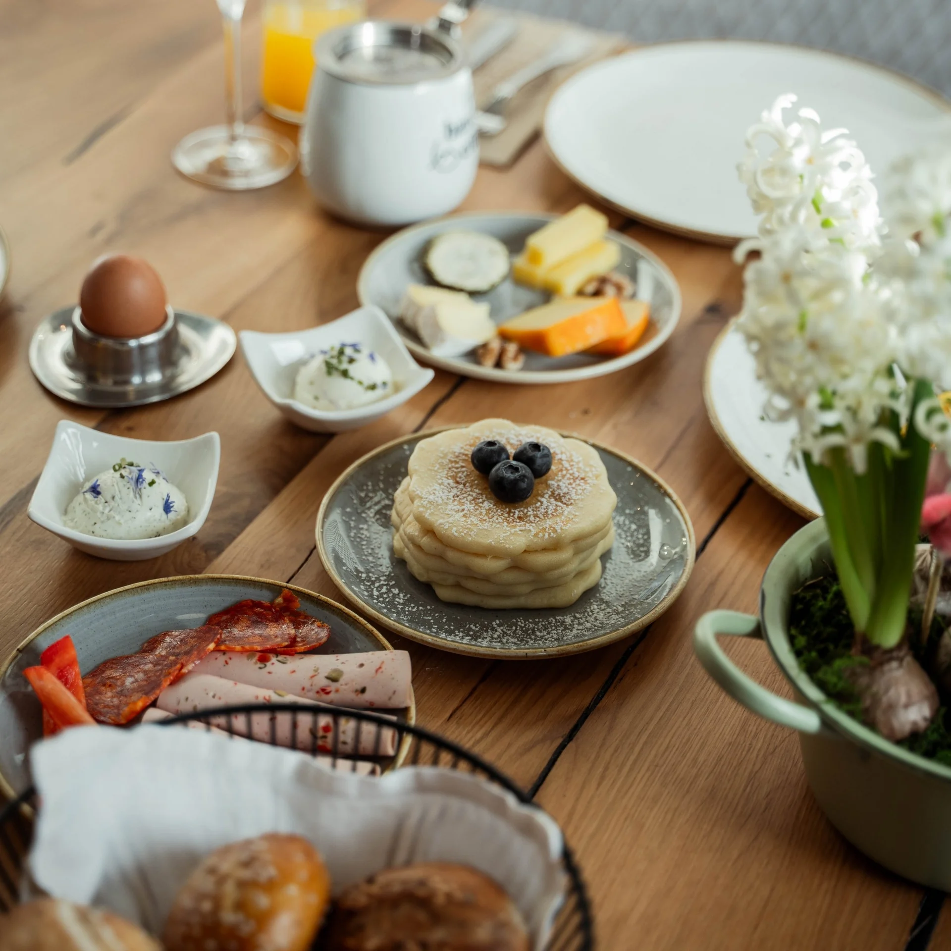 Kulinarik Frühstückstisch mit Pfannkuchen, Käse, Wurst, Ei und Brötchen