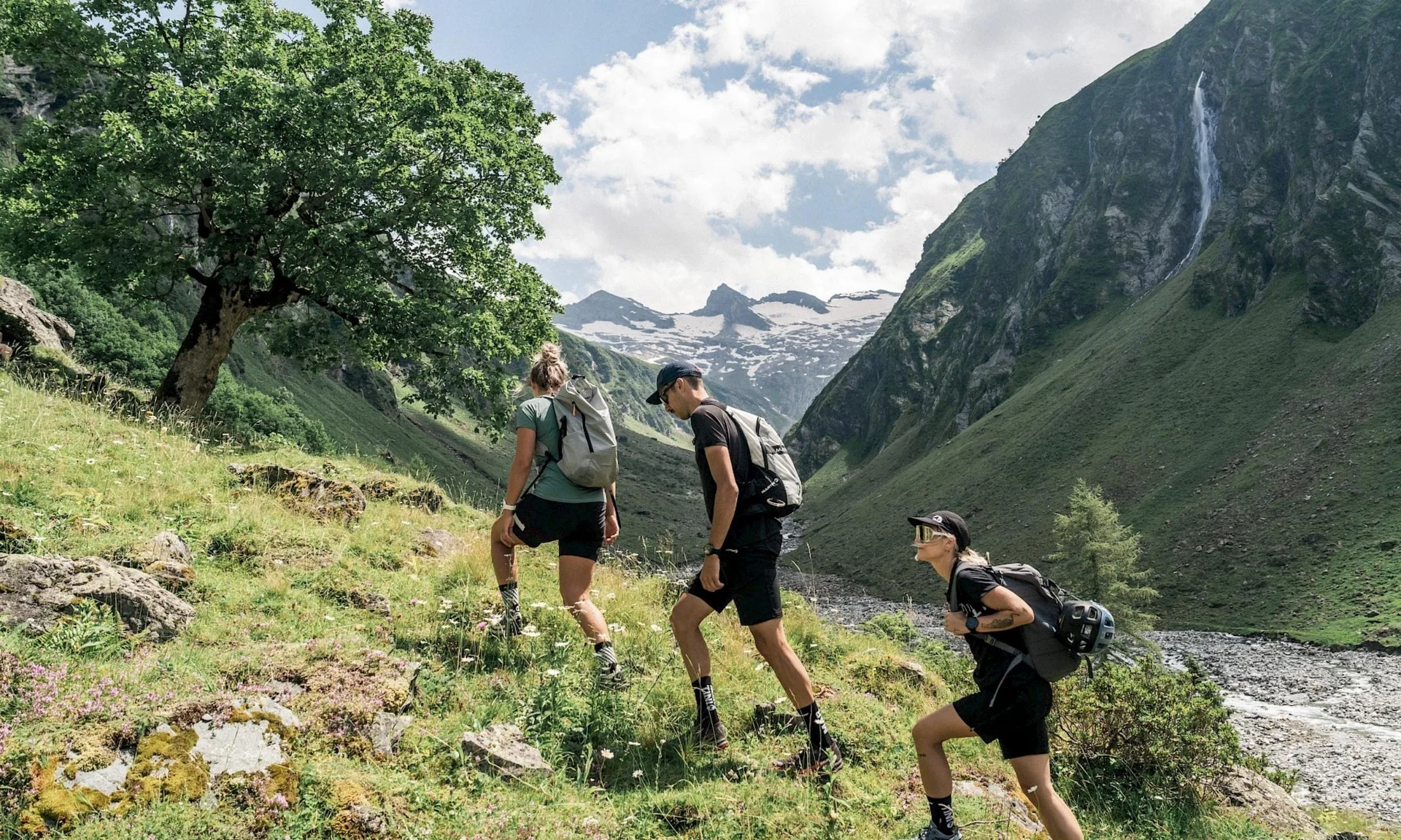 Wanderhotel Drei Wanderer steigen in den Bergen an einem sonnigen Tag auf