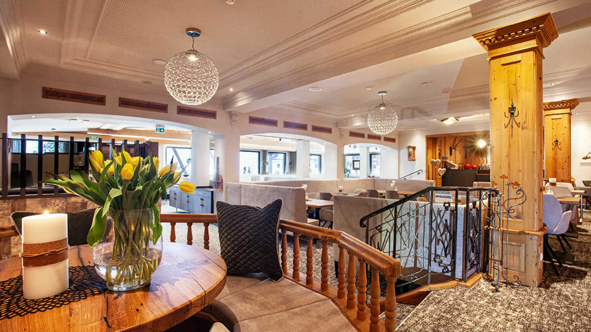 Das Hotel Gemütliches Restaurantinterieur mit Holztischen, gelben Tulpen und modernen Leuchten