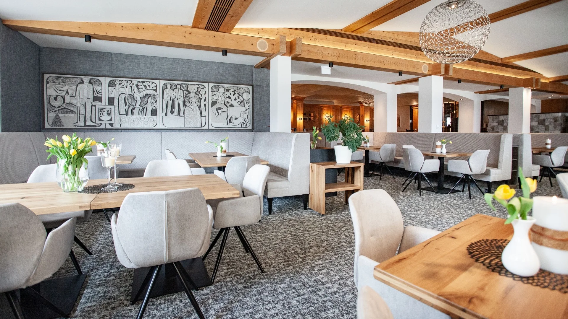Kulinarik Helles modernes Restaurant mit Holztischen, grauen Stühlen und frischen Blumen auf den Tischen