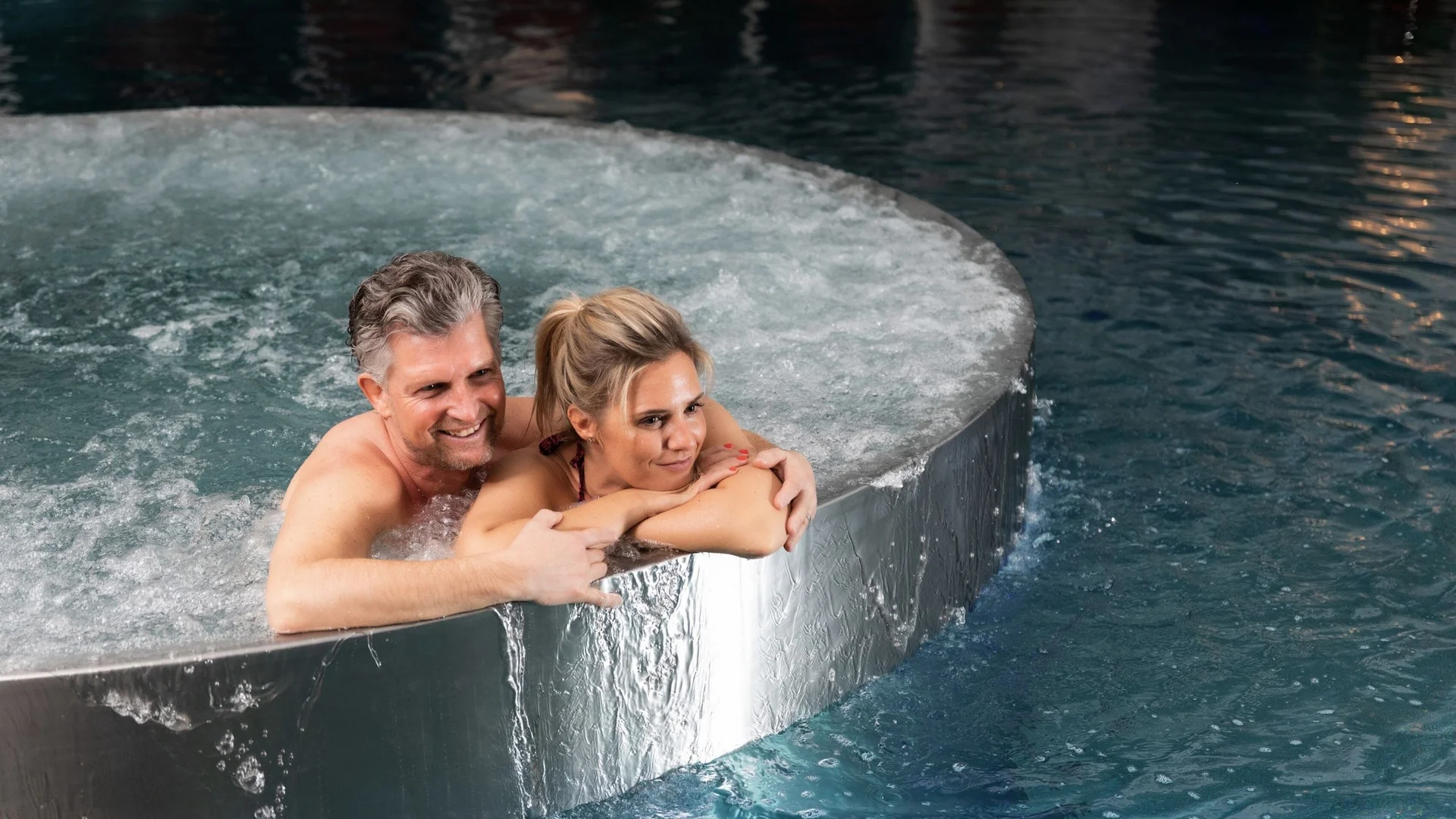 Saunawelt Paar entspannt im Whirlpool mit sprudelndem Wasser am Pool