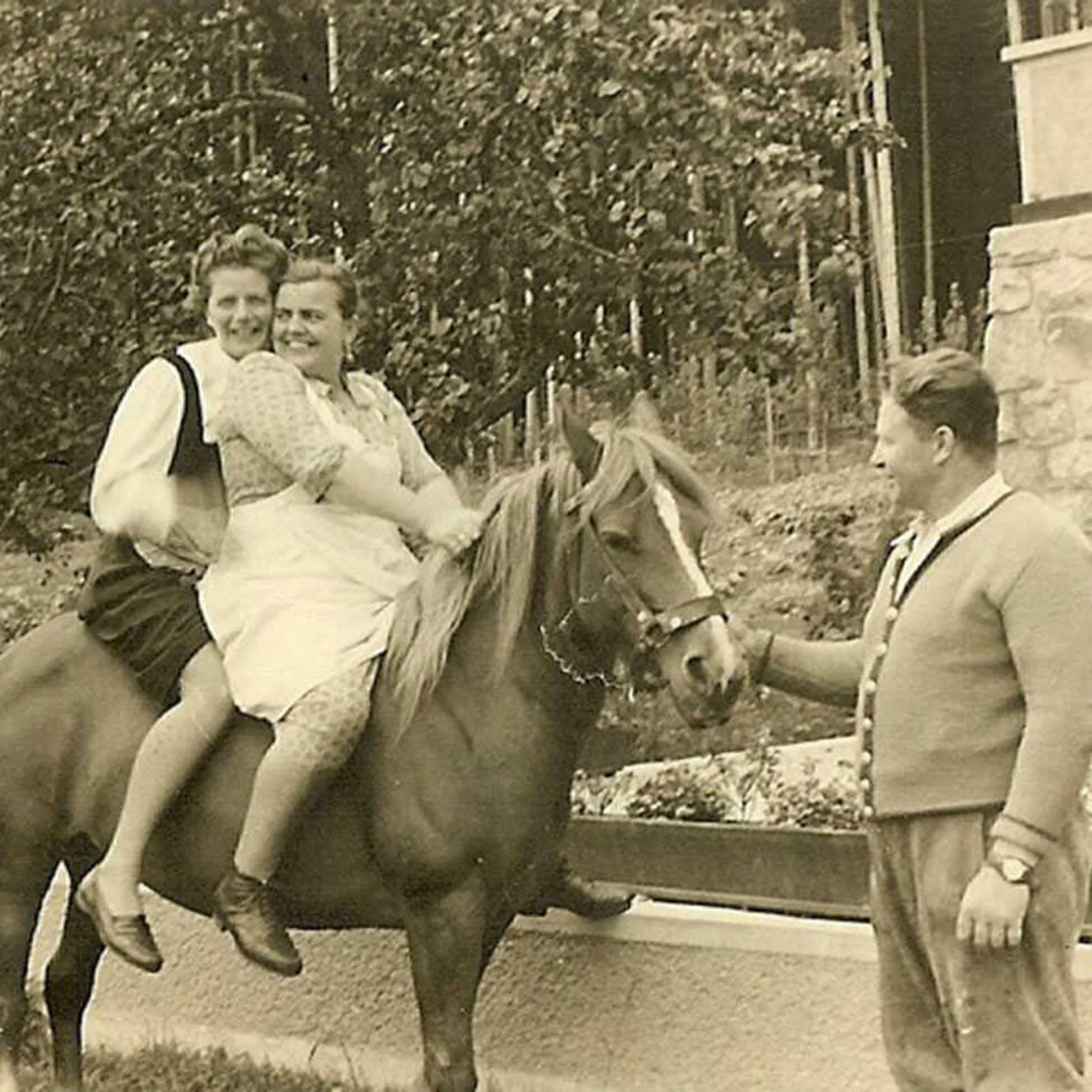 Das Hotel Zwei Frauen sitzen auf einem Pferd, ein Mann hält das Pferd an einem Bauernhof