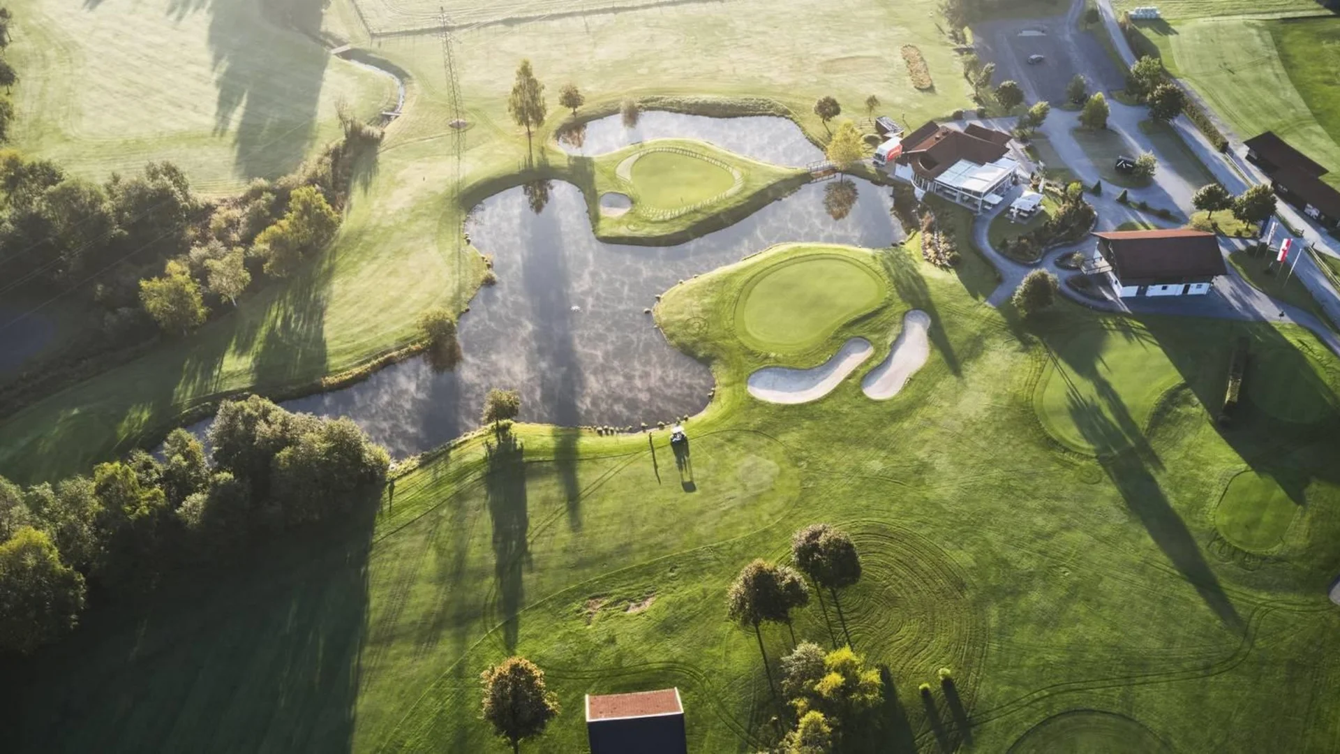 Golfen Luftaufnahme eines Golfplatzes mit Teichen und Clubgebäuden bei Sonnenlicht