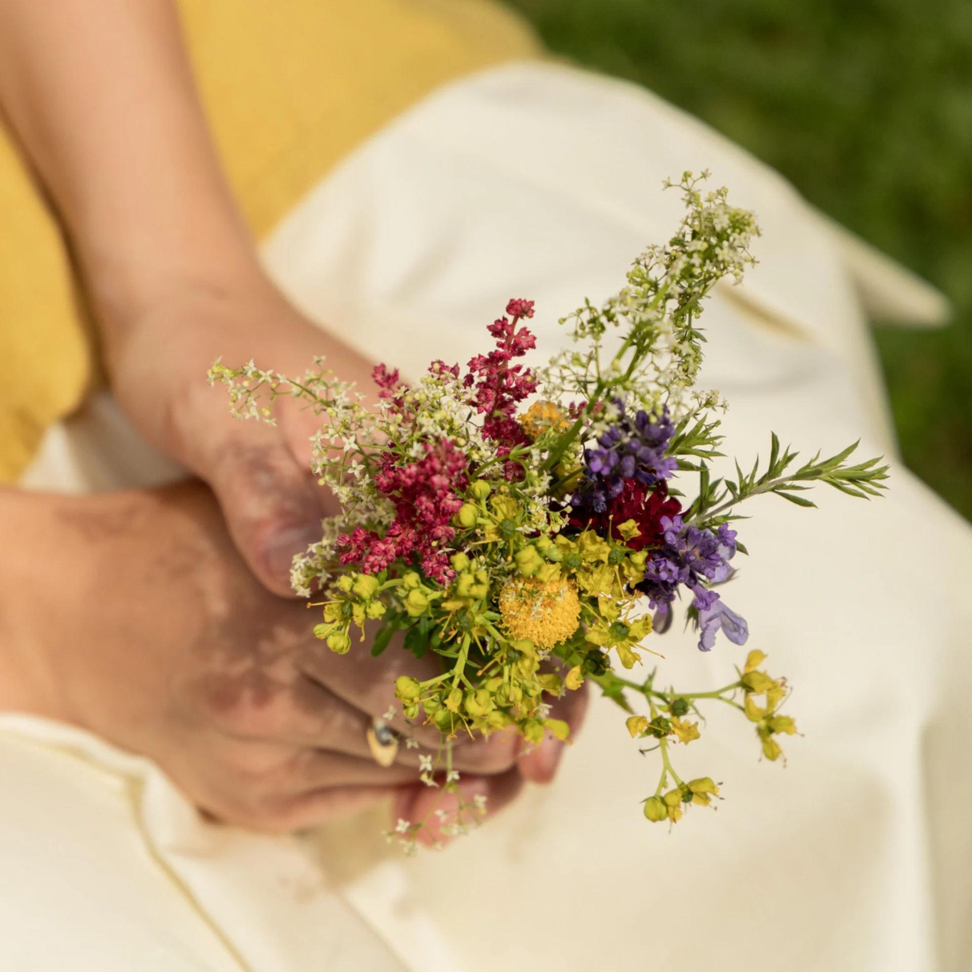 Unsere Werte Person hält kleinen bunten Blumenstrauß auf weißem Stoff