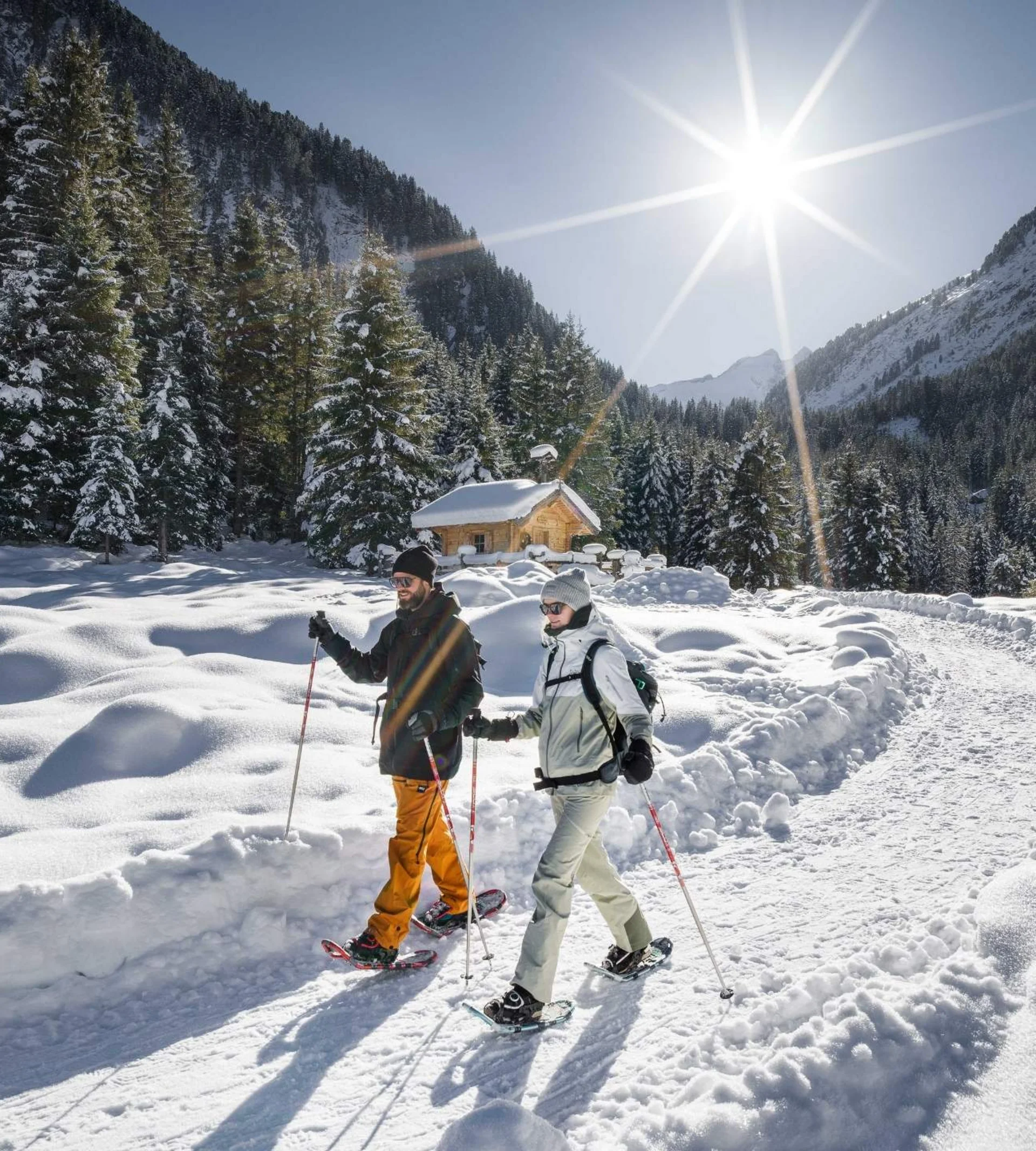 Abseits der Piste Zwei Personen beim Schneeschuhwandern auf verschneitem Bergweg im Sonnenschein
