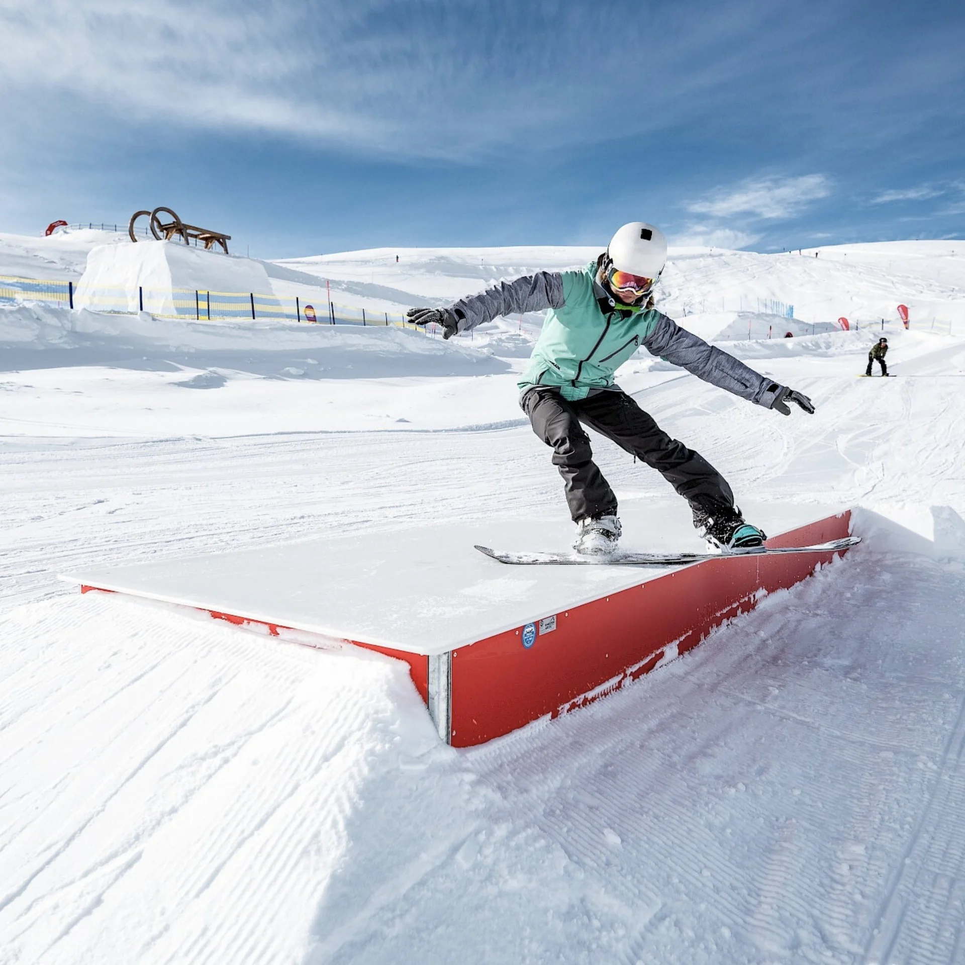 Bergwinter Snowboarder fährt auf einer roten Schiene im Schnee bei sonnigem Wetter