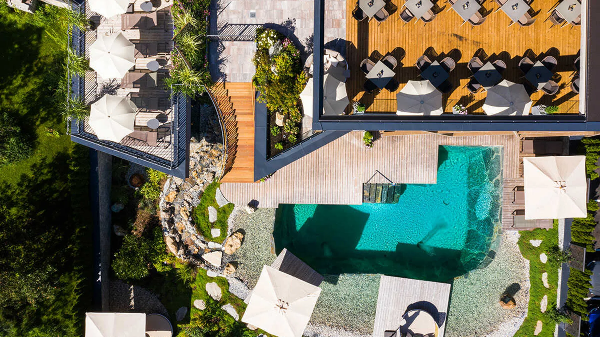Das Hotel Luftaufnahme von Terrasse mit Tischen, Stühlen, Sonnenschirmen und einem Pool
