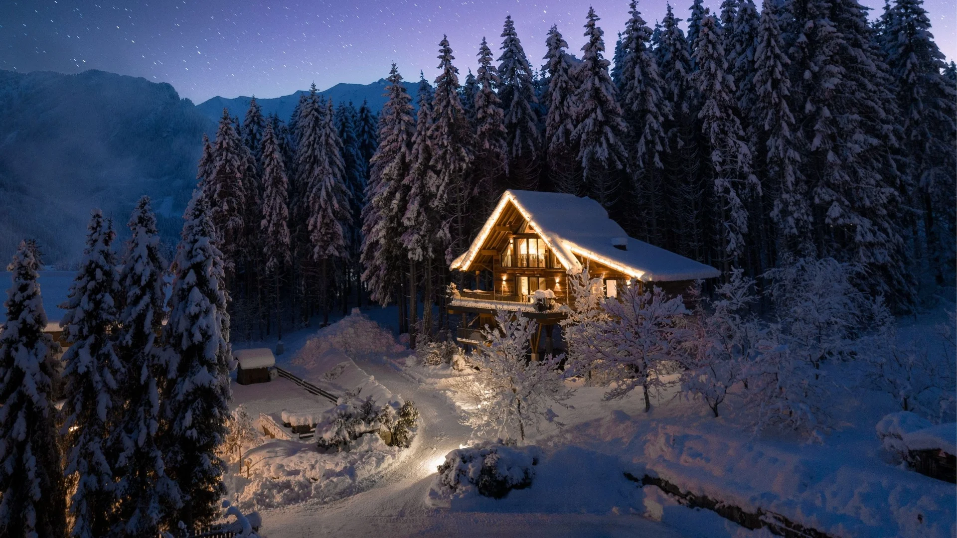 Home Schneebedecktes Chalet im Wald bei Nacht mit beleuchteten Außenlichtern