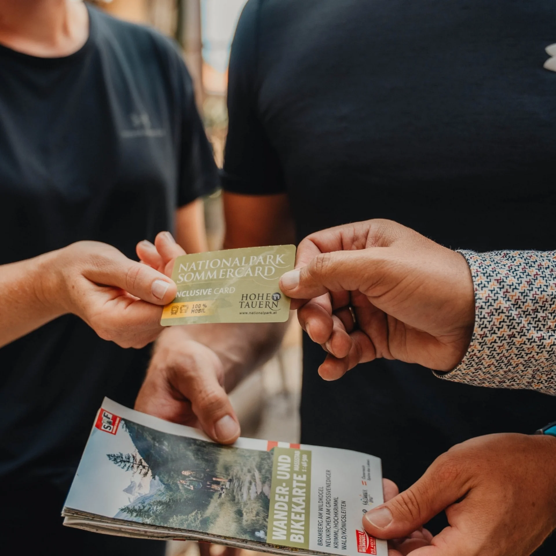 Bergsommer Person übergibt Nationalpark Sommercard an anderen, hält Wander- und Bikerkarte
