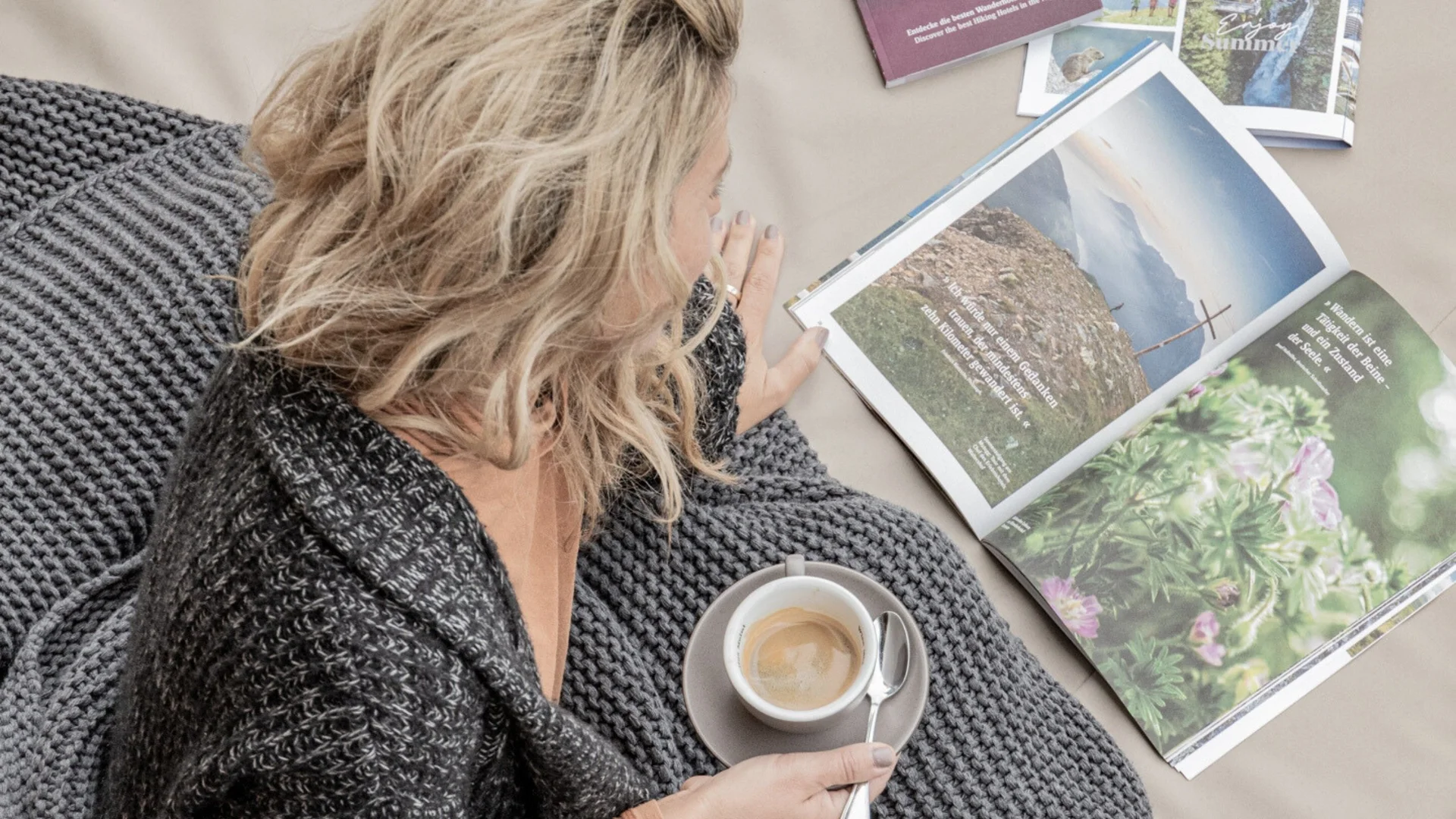 Baumhaus Frau liest Magazin und hält Tasse Kaffee im grauen Strickpullover