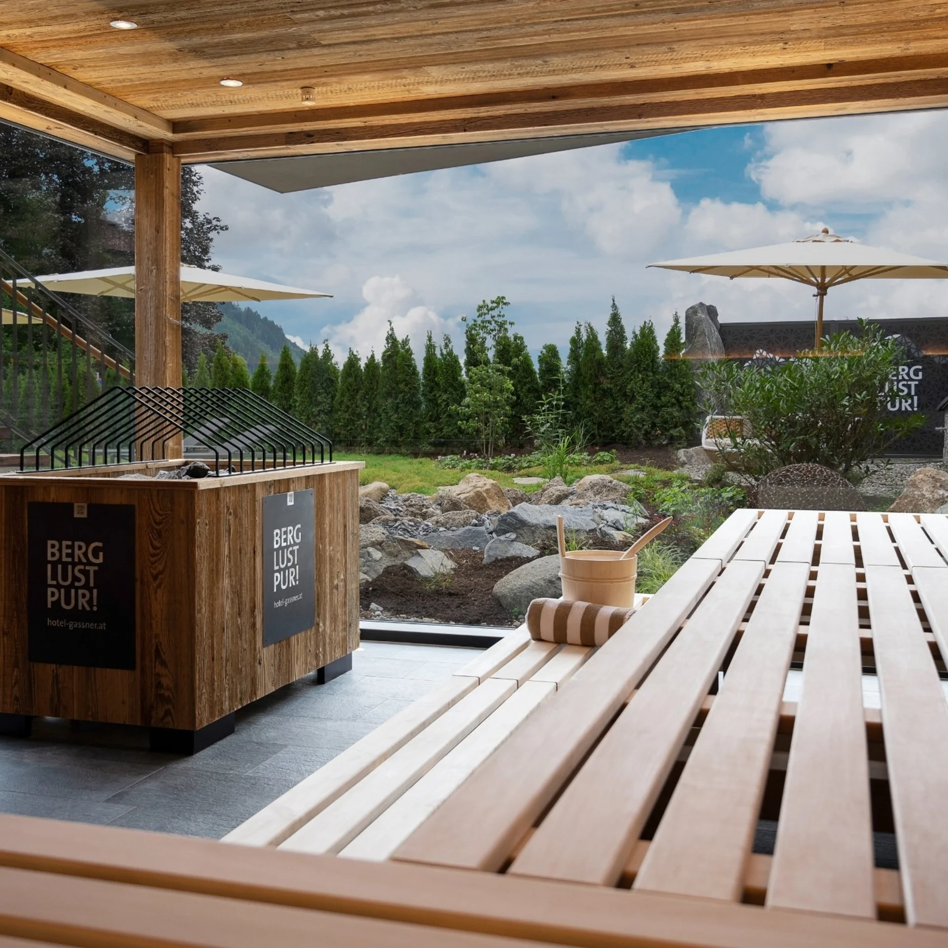 Saunawelt Moderner Holzsauna mit Blick auf Garten und Berge bei Tageslicht