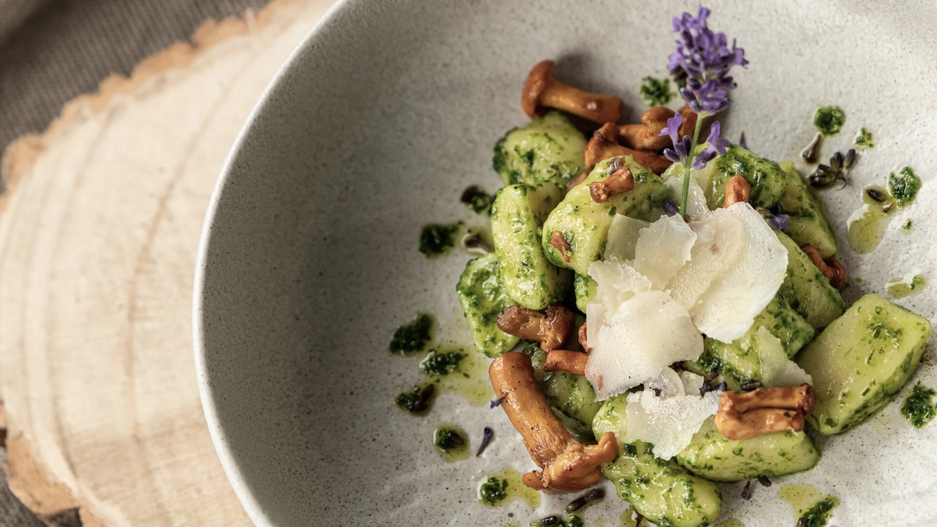 Golfen Gnocchi mit Pilzen, Pesto, Parmesan und Lavendelblüte auf einem grauen Teller