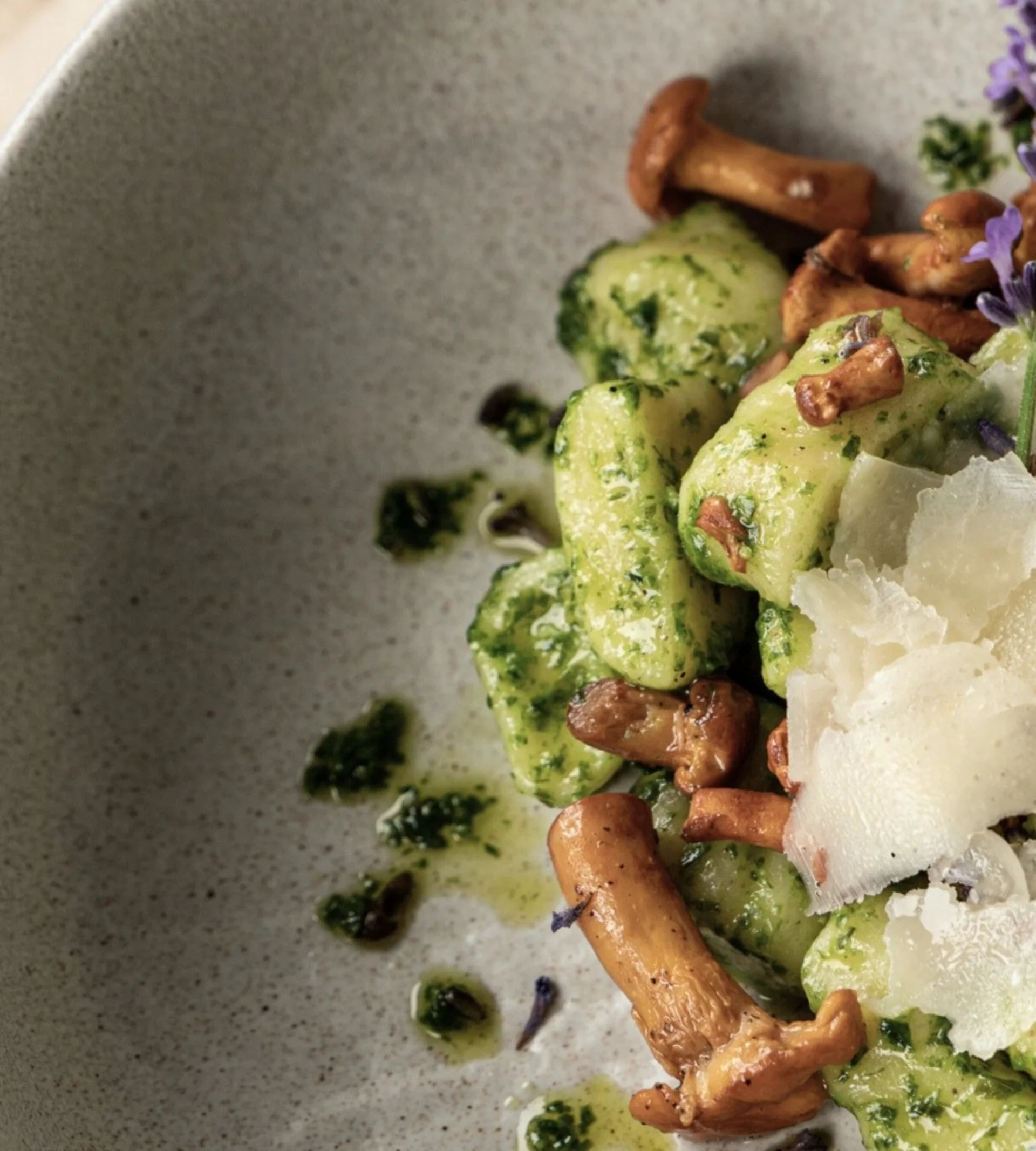 Golfen Gnocchi mit Pilzen, Pesto, Parmesan und Lavendelblüte auf einem grauen Teller