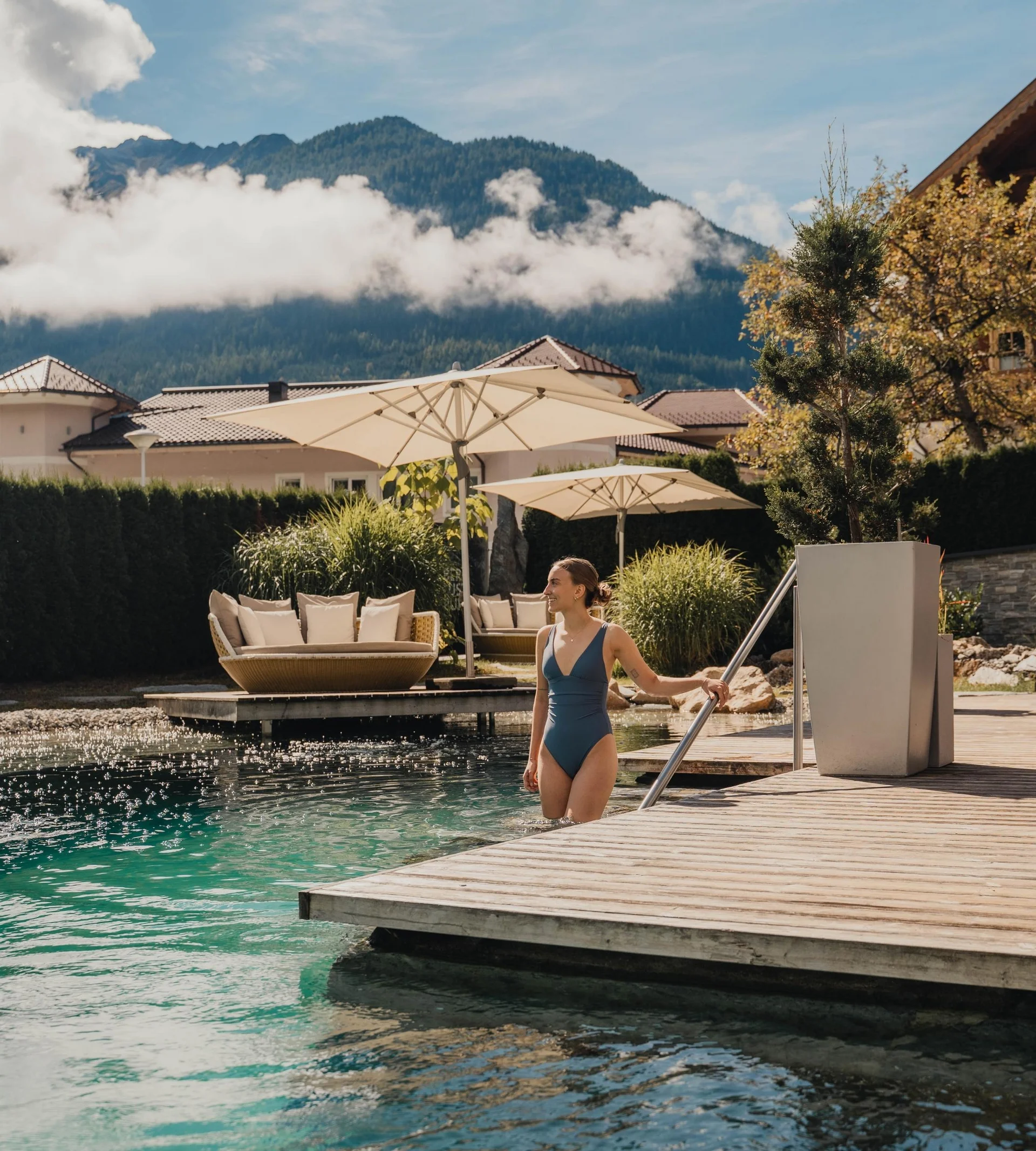 Biken Frau steigt in Pool an sonnigem Tag mit Bergen und Liegen im Hintergrund