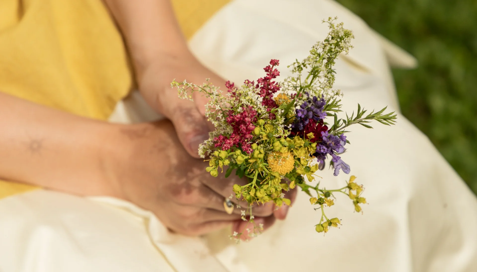 Gassner-Blog Person hält einen bunten Frühlingsblumenstrauß in der Hand