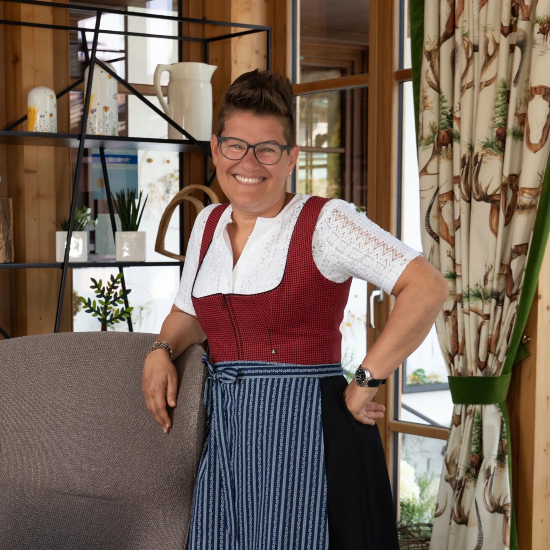 Jobs Lächelnde Frau in Tracht lehnt an Stuhl in gemütlichem Raum