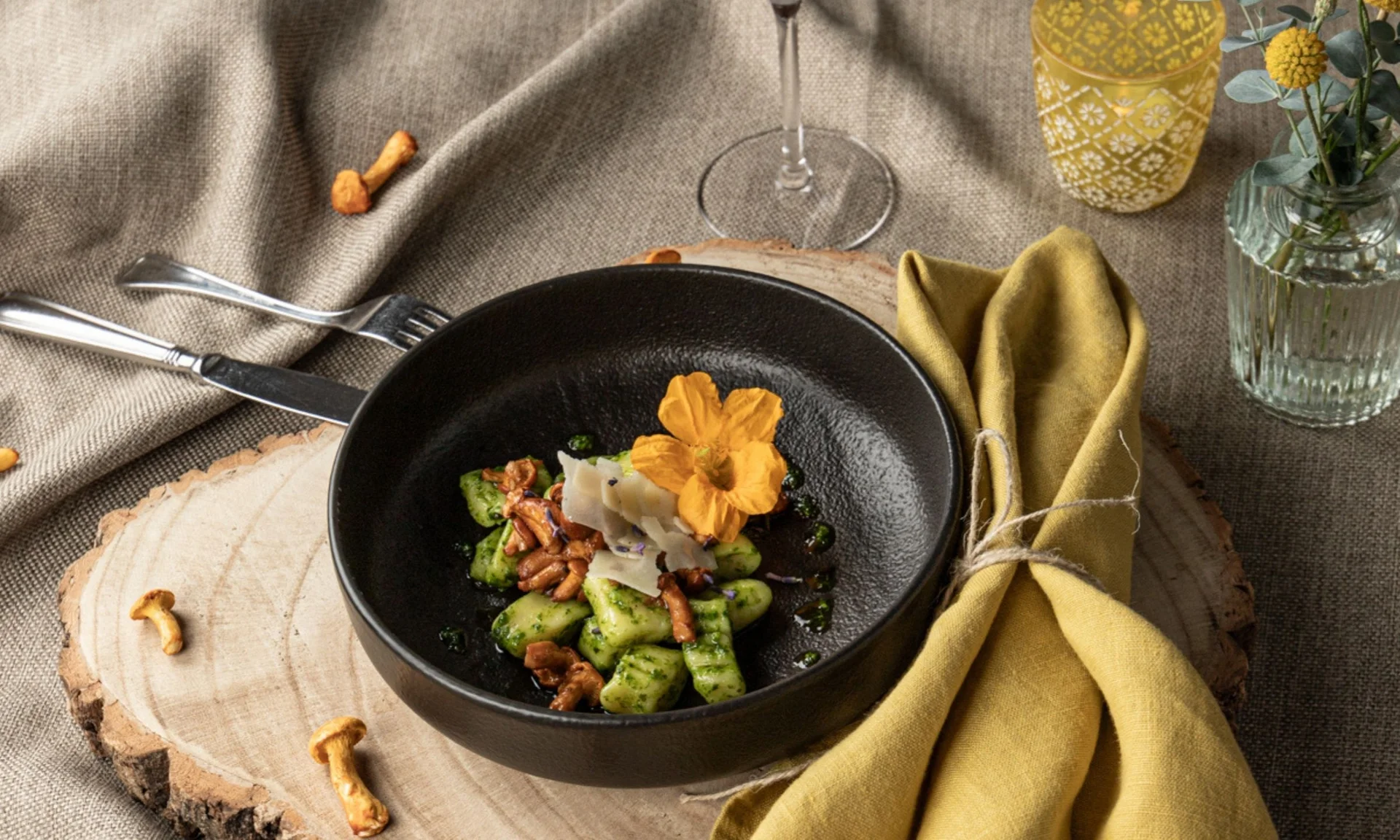 Home Schwarze Schale mit Gnocchi, Pilzen und essbarer Blume auf Holzbrett