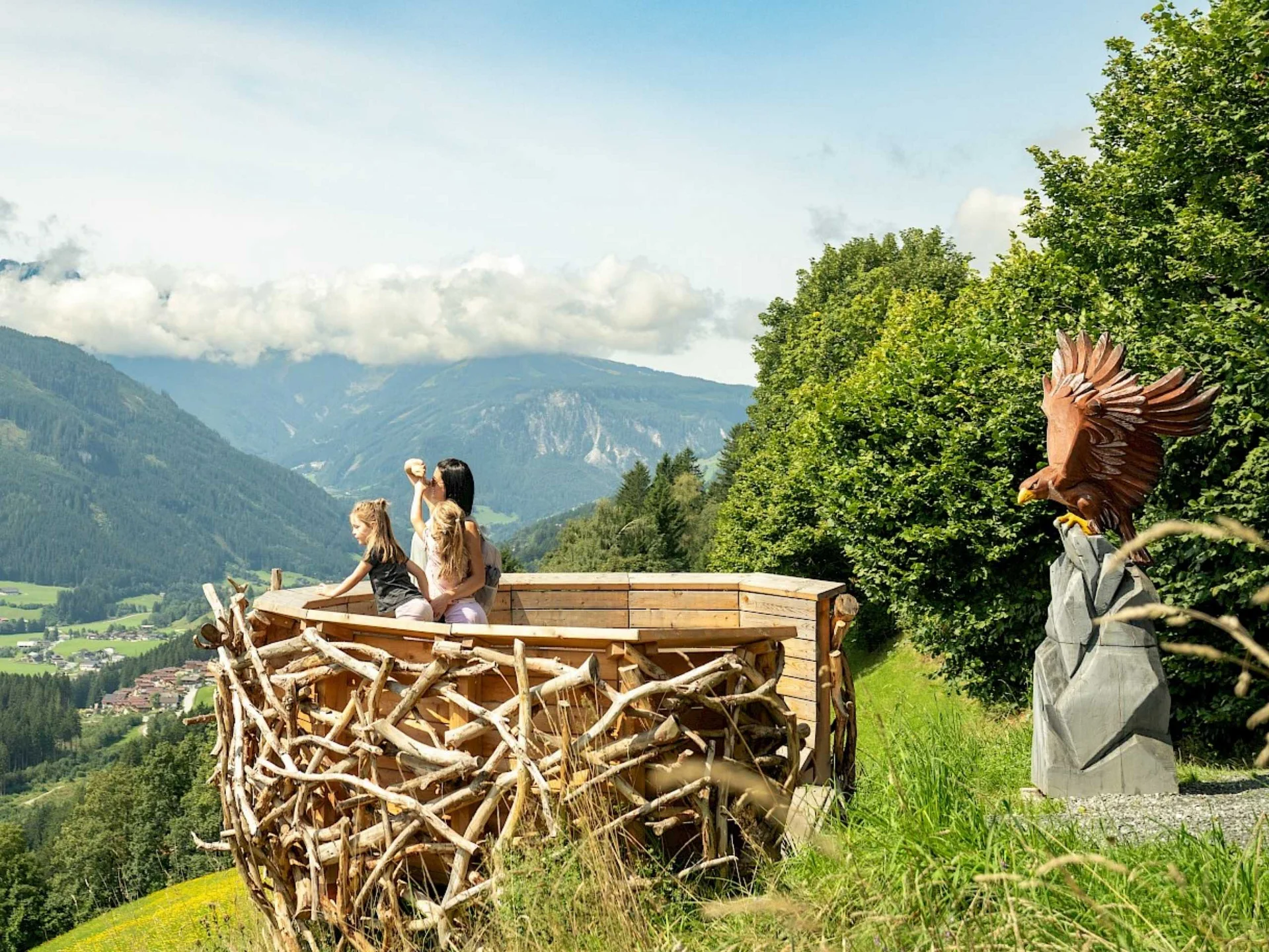 Nationalpark Sommercard Familie auf Holzaussichtsplattform des Adler-Toni-Erlebnisweges mit Bergblick in der Wildkogel-Arena