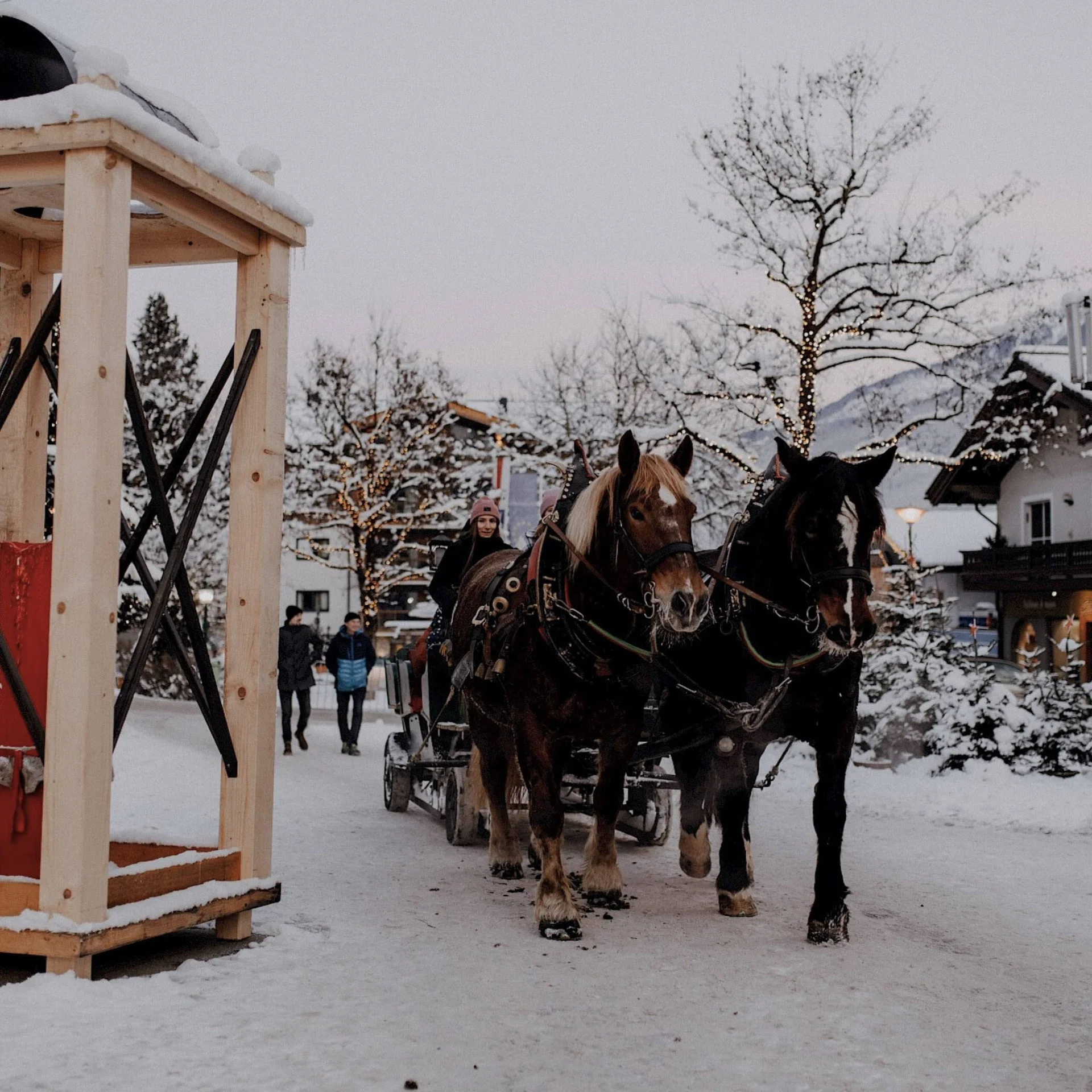 Familienzeit Pferdekutsche mit zwei Pferden fährt durch die verschneite Straße von Neukirchen am Großvenediger im Winter