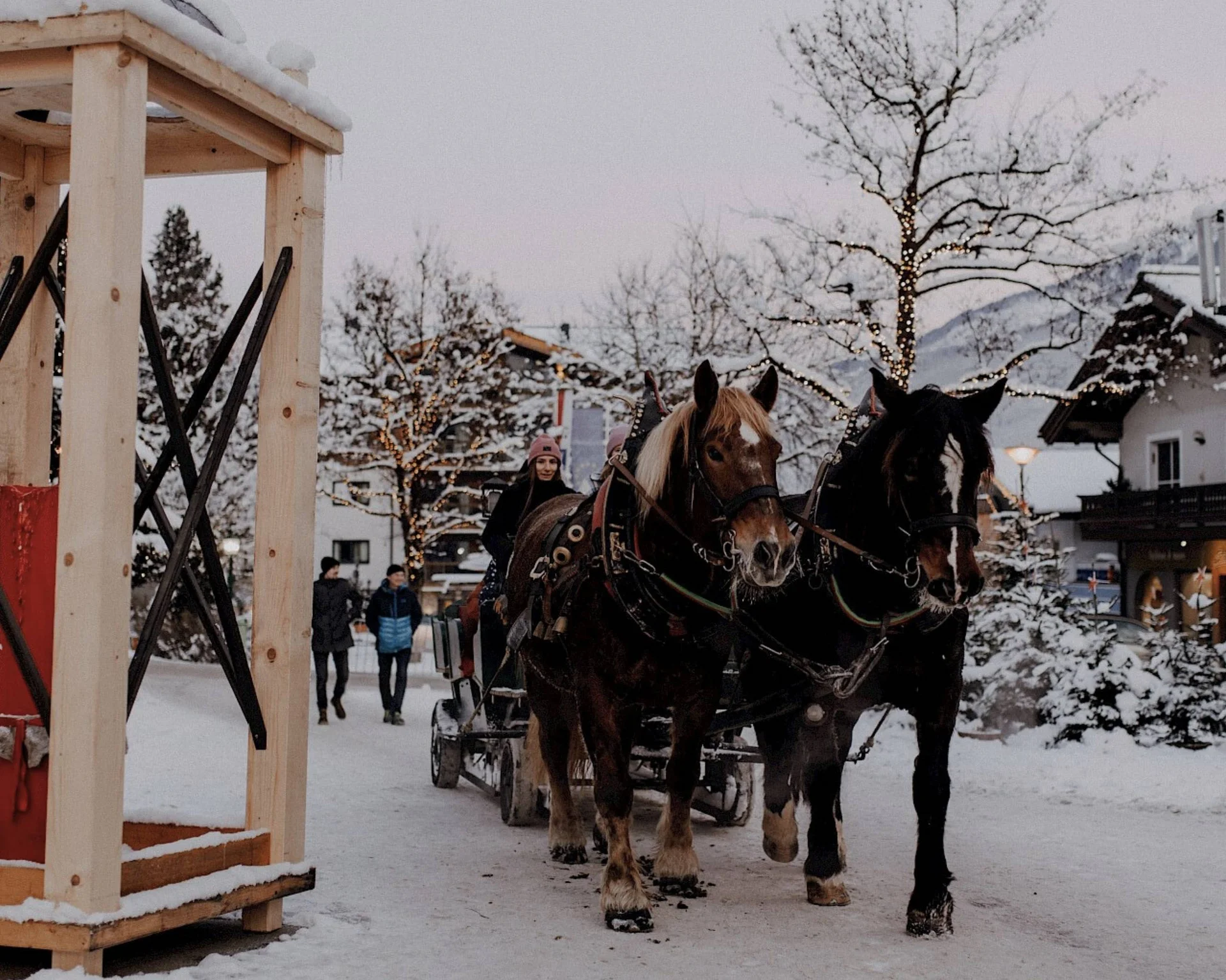 Ausflugstipps Pferdekutsche mit zwei Pferden fährt durch die verschneite Straße von Neukirchen am Großvenediger im Winter