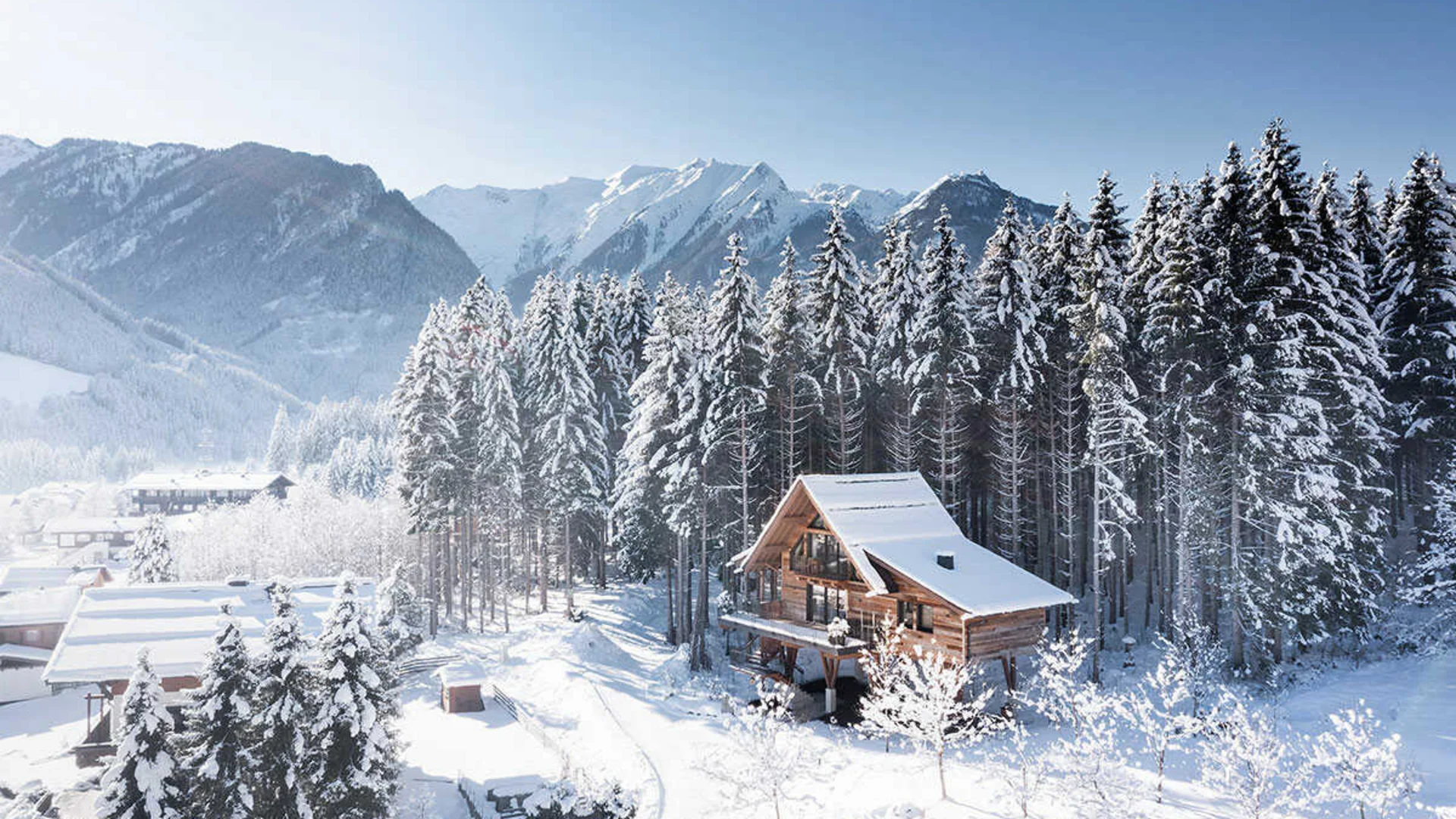 Das Hotel Verschneite Holzhütte vor Tannenwald und Bergen im Winter