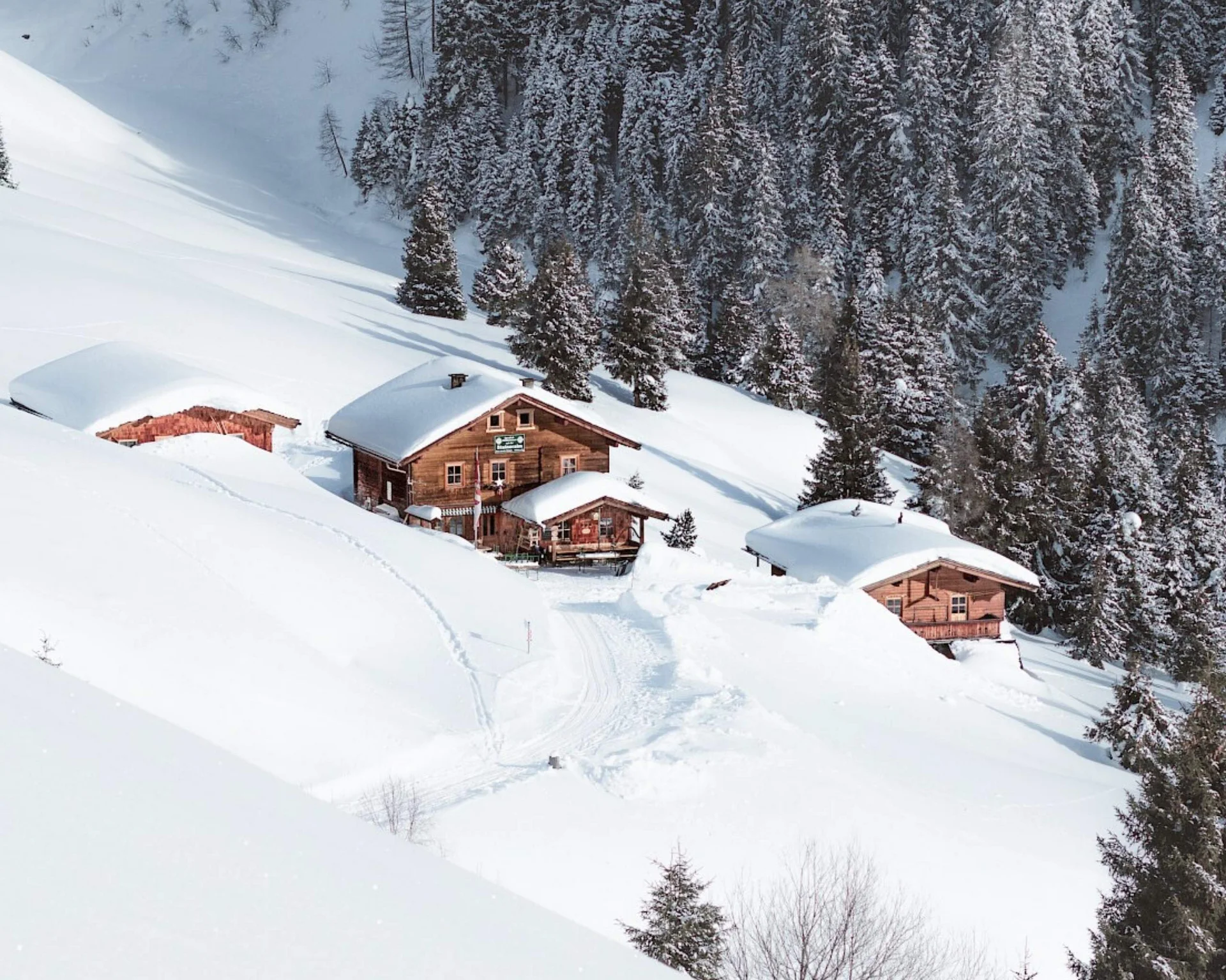 Ausflugstipps Verschneite Holzhäuser in einem Tal neben einem Wald im Winter