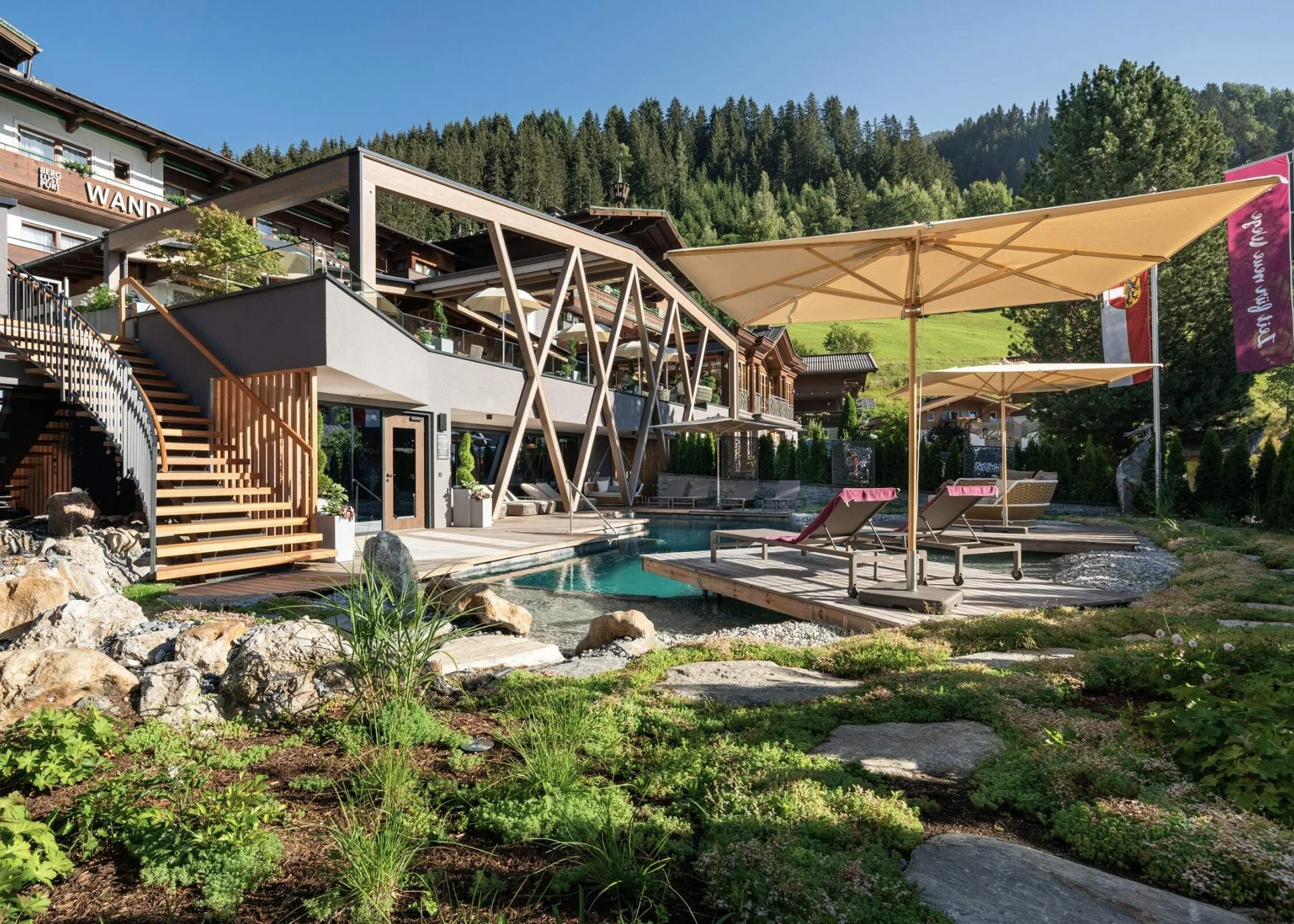 Golfen Moderner Hotelgarten mit Pool, Liegestühlen, Sonnenschirmen und Bergkulisse