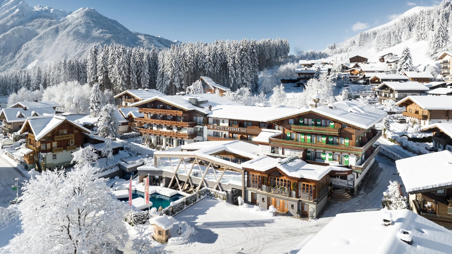 Bergwinter Verschneite Berglandschaft mit Hotel und Bäumen im Winter