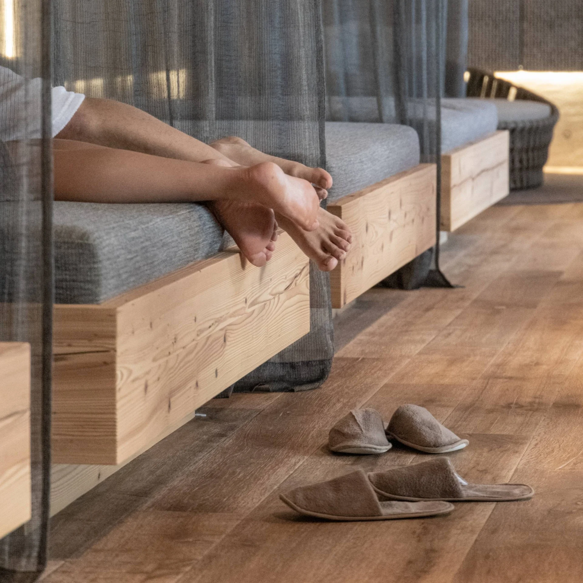 Wellness Füße auf einer Holzbank mit Hausschuhen auf Holzfußboden