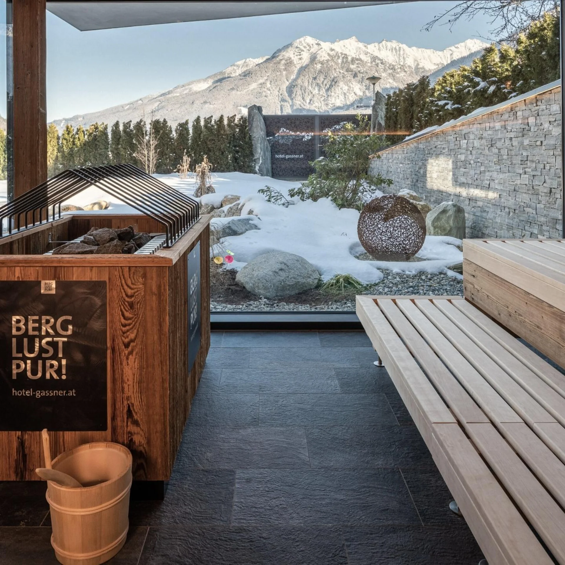 Saunawelt Sauna mit Panoramafenster auf schneebedeckte Berge und Garten