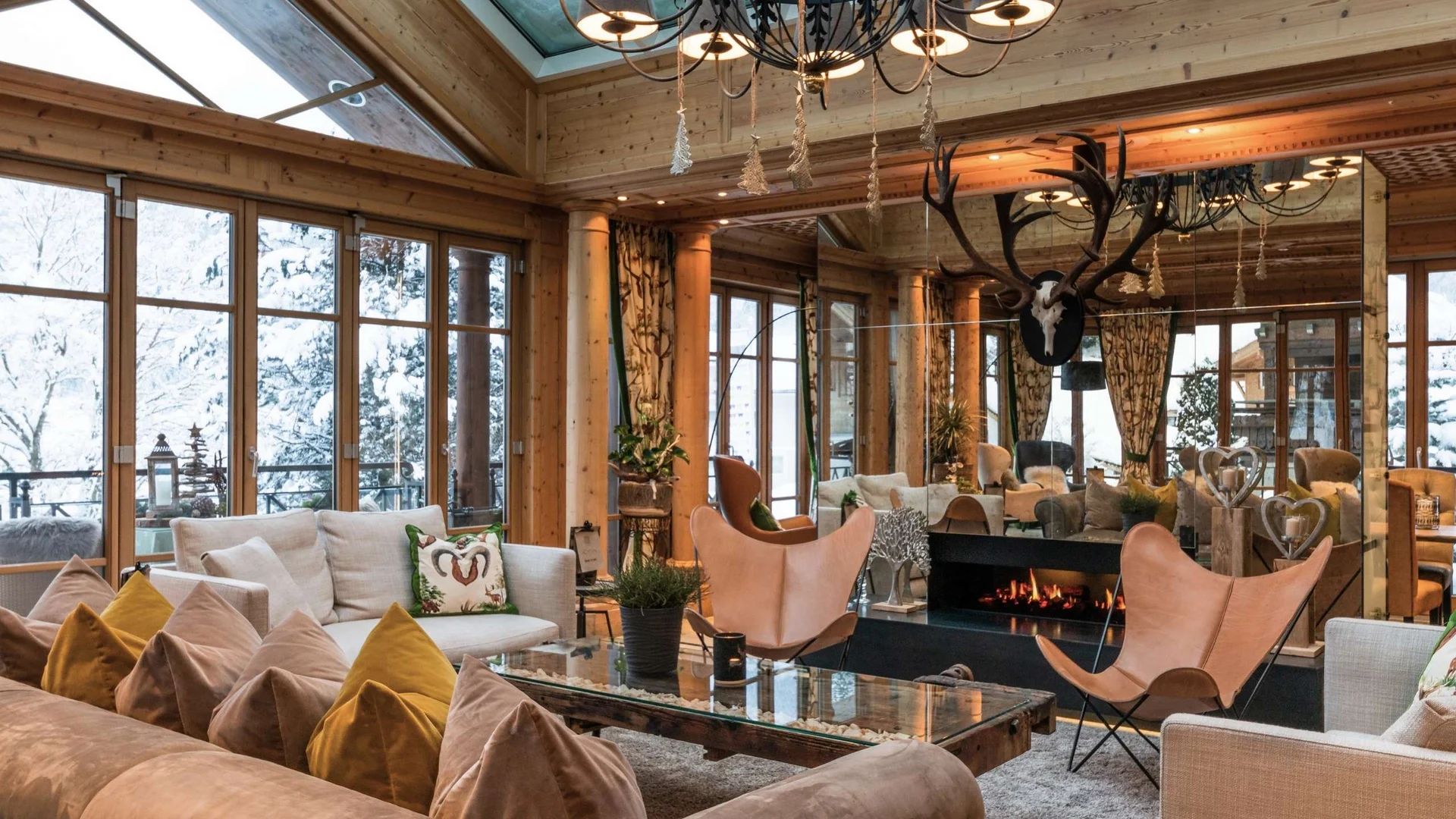 Wohnen Gemütliches Wohnzimmer mit Holzwänden, Kamin und großen Fenstern im Winter