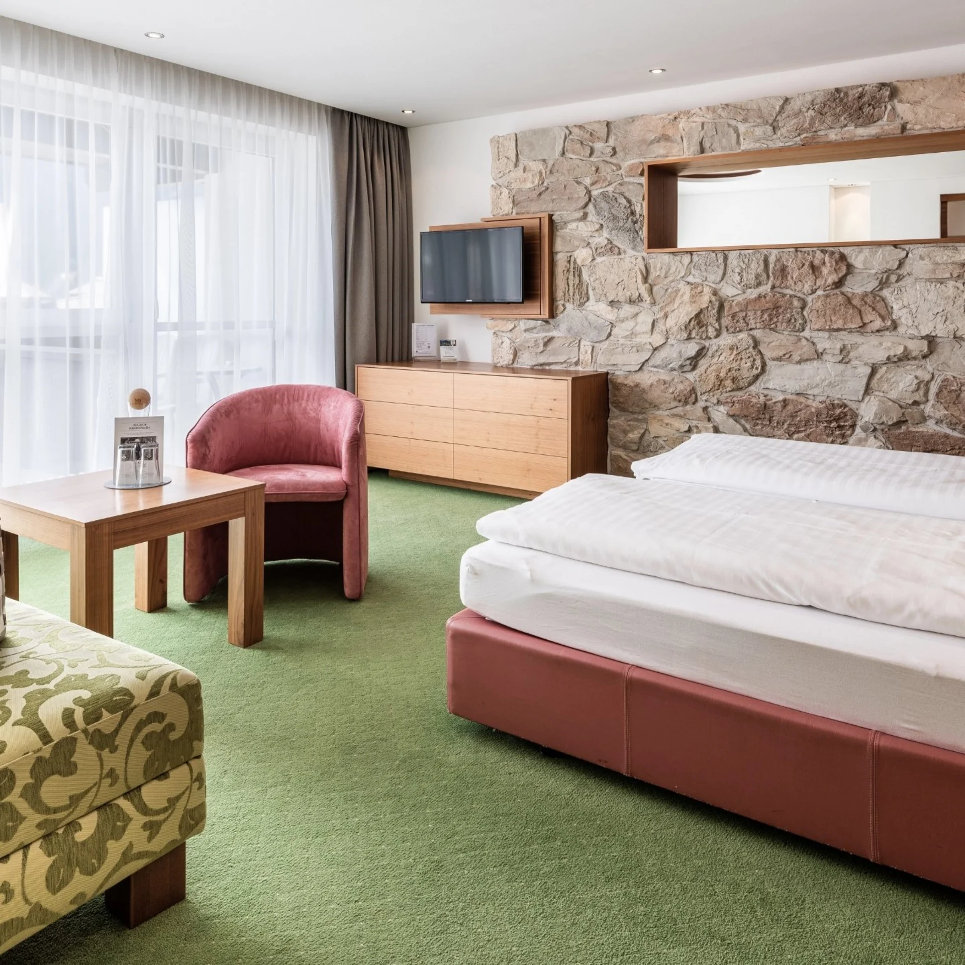 Wohnen Gemütliches Hotelzimmer mit Doppelbett, Steinwand und Sitzbereich