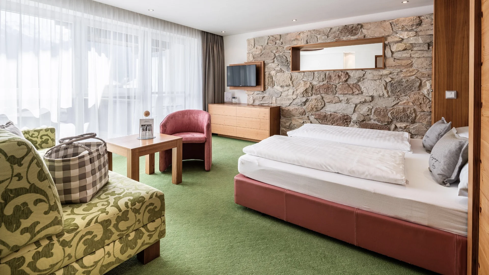 Wohnen Gemütliches Hotelzimmer mit Doppelbett, Steinwand und Sitzbereich