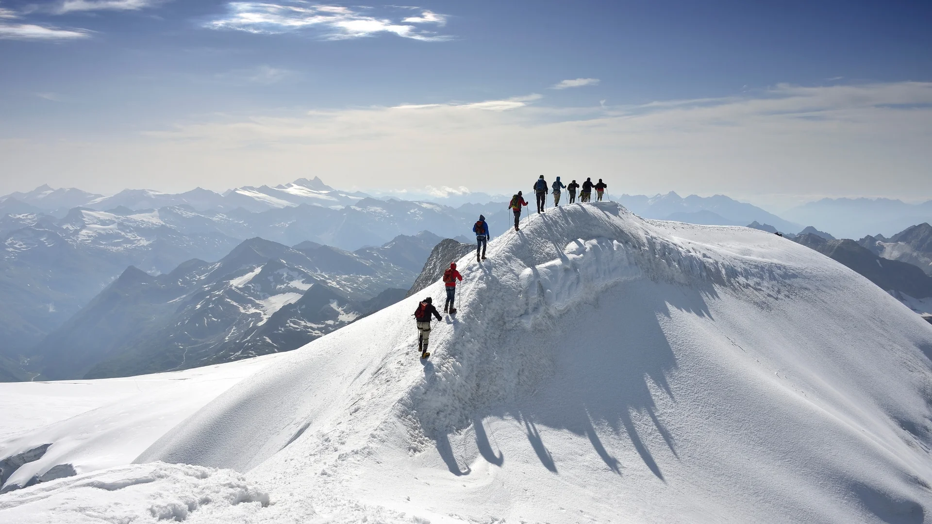 Großvenediger Gruppe von Bergsteigern wandert auf schneebedecktem Berggipfel bei klarem Wetter