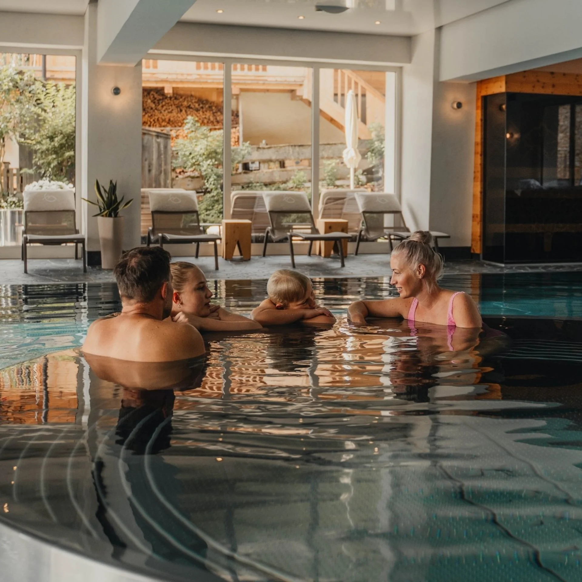 Familienzeit Vier Personen entspannen in einem beheizten Innenpool in einem Spa