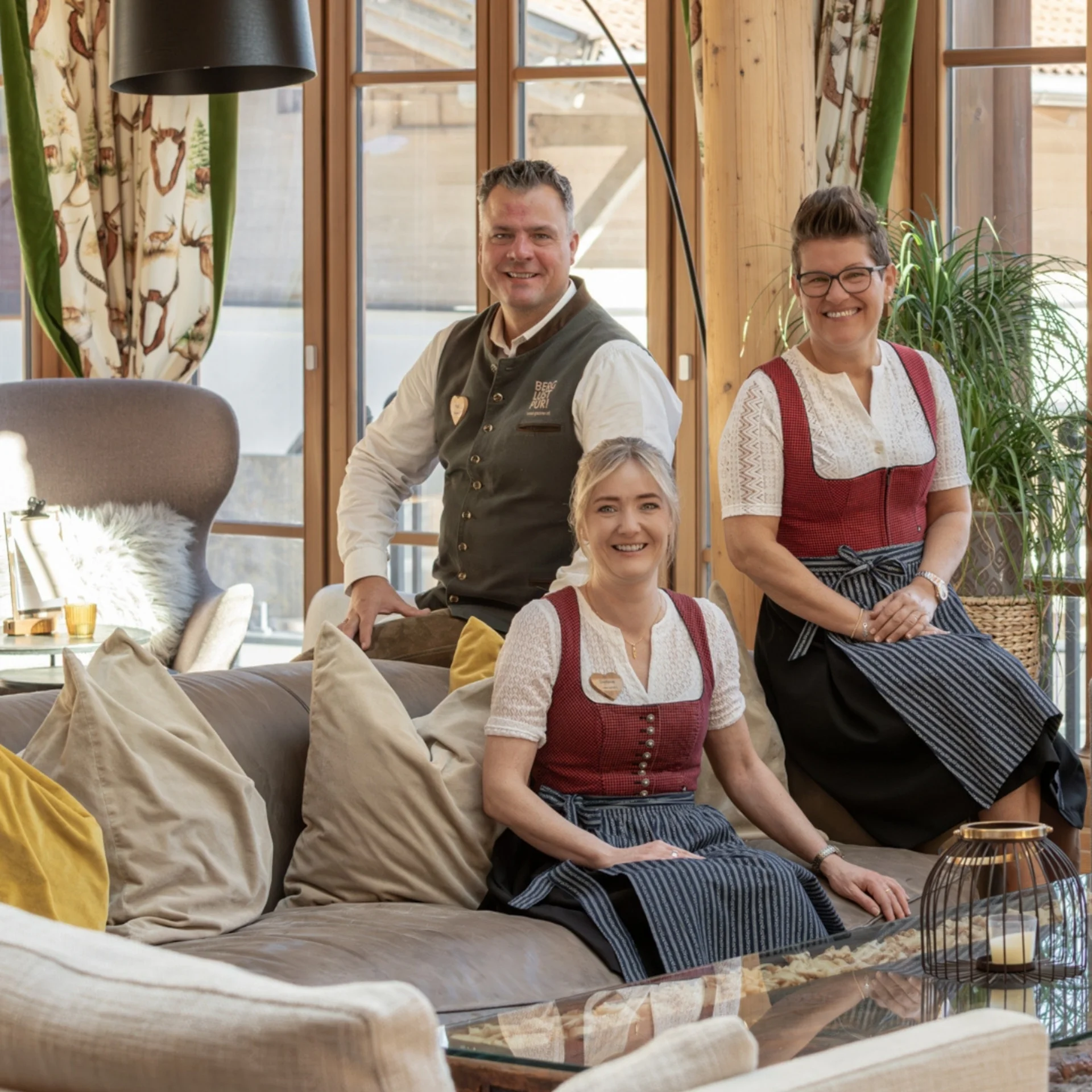 Baumhaus Vier Personen in Trachten sitzen am Holzsteg neben einem Naturteich