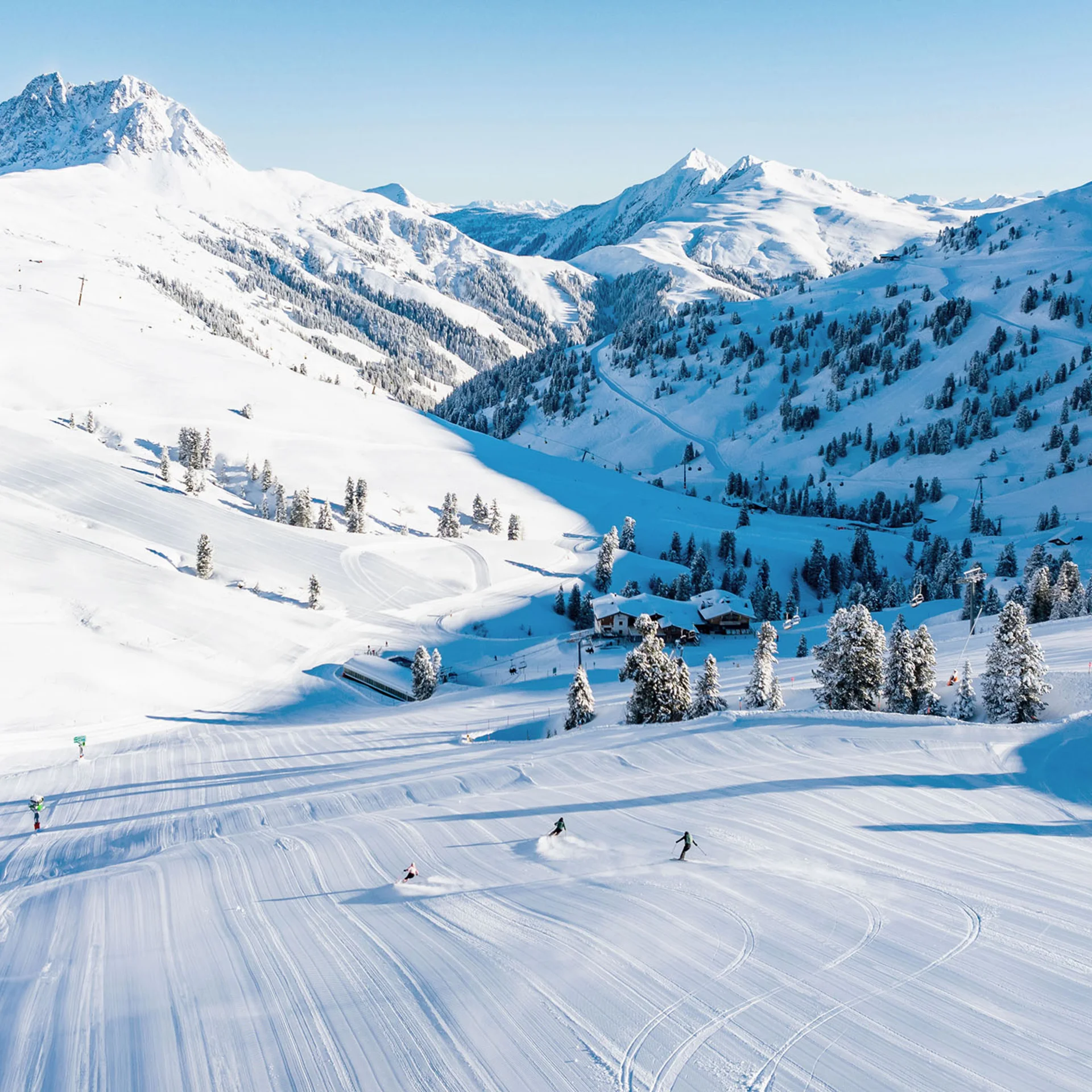 Bergwinter Skifahrer auf verschneiter Piste in den Alpen bei klarem Himmel