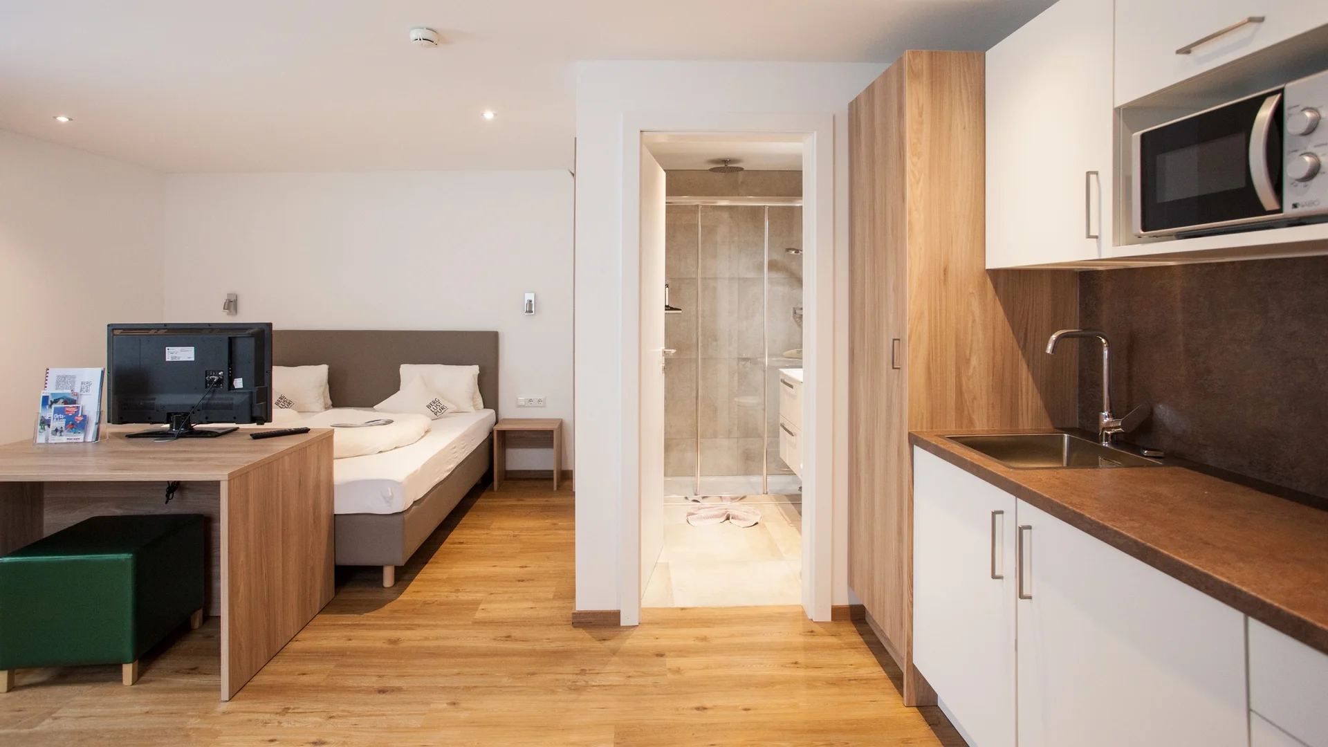 Benefits im Hotel Modernes Hotelzimmer mit Bett, Schreibtisch, Küchenzeile und Bad