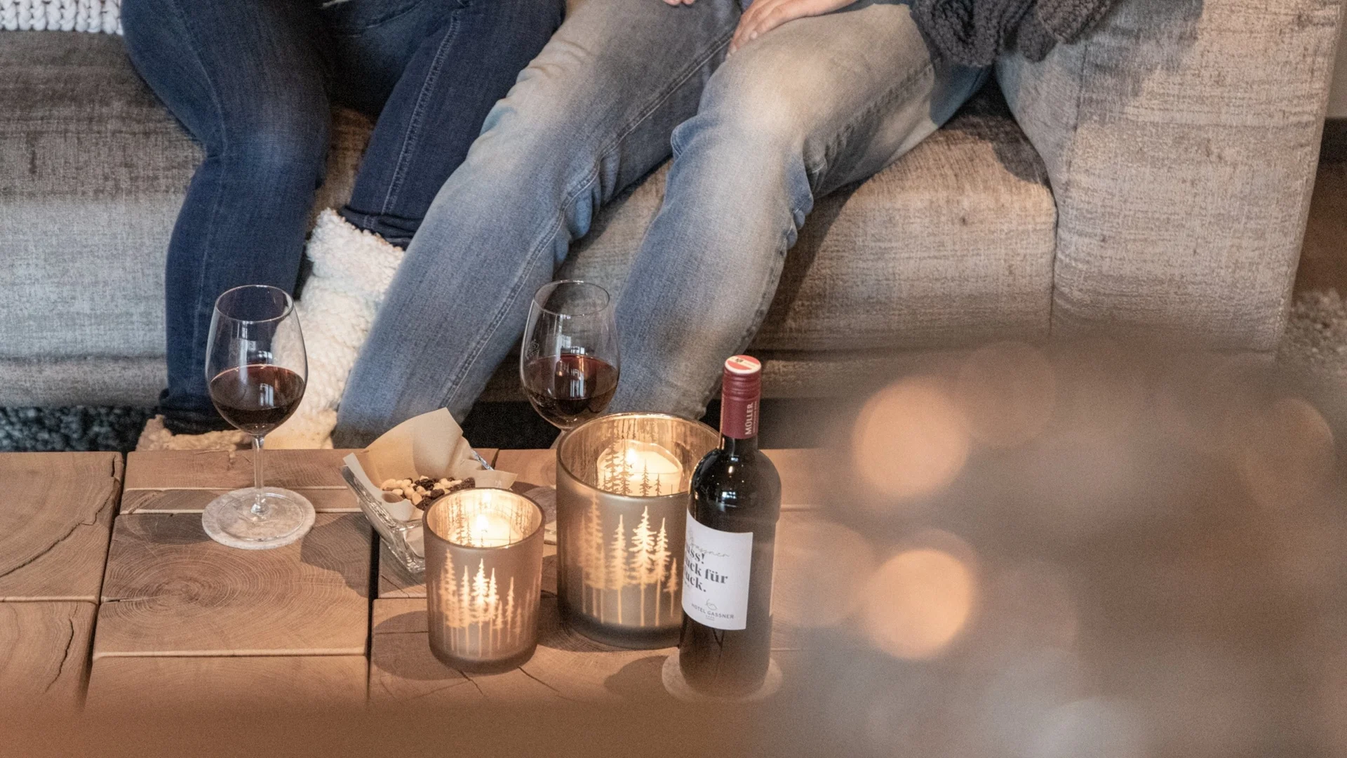 Baumhaus Zwei Leute sitzen auf einem Sofa mit Wein und Kerzen auf dem Holztisch