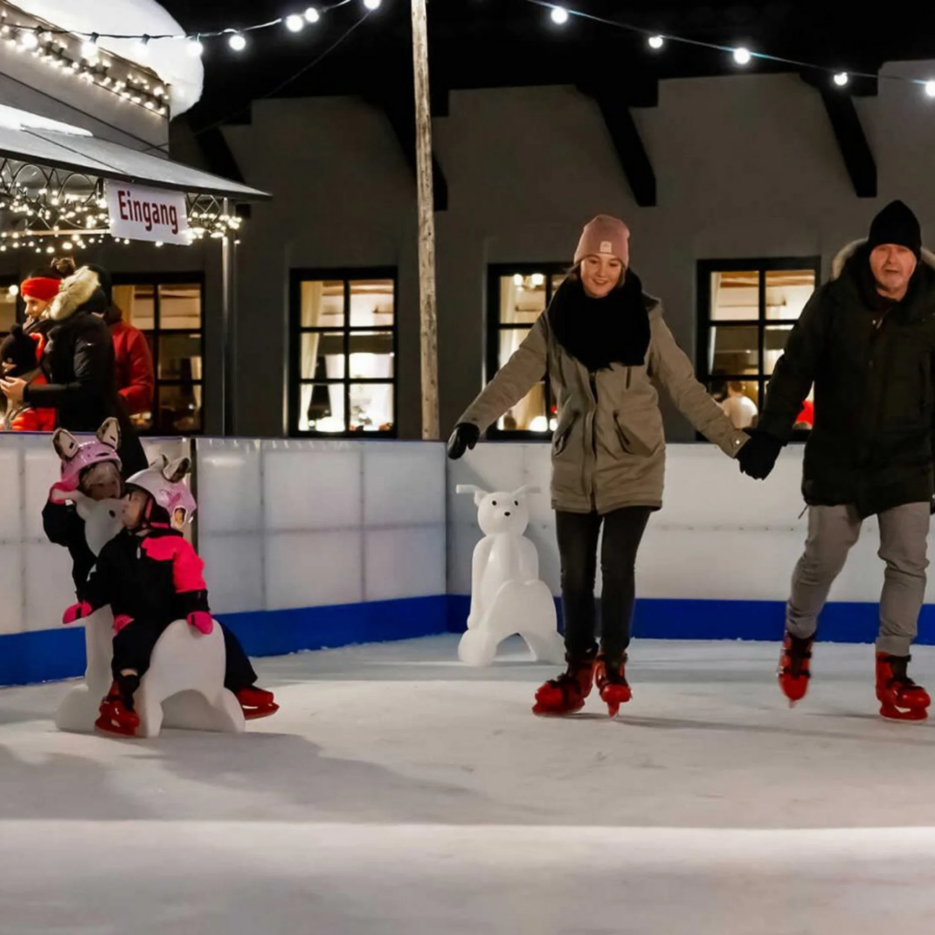 Abseits der Piste Familie und Kinder beim abendlichen Schlittschuhlaufen auf einer künstlichen Eisbahn