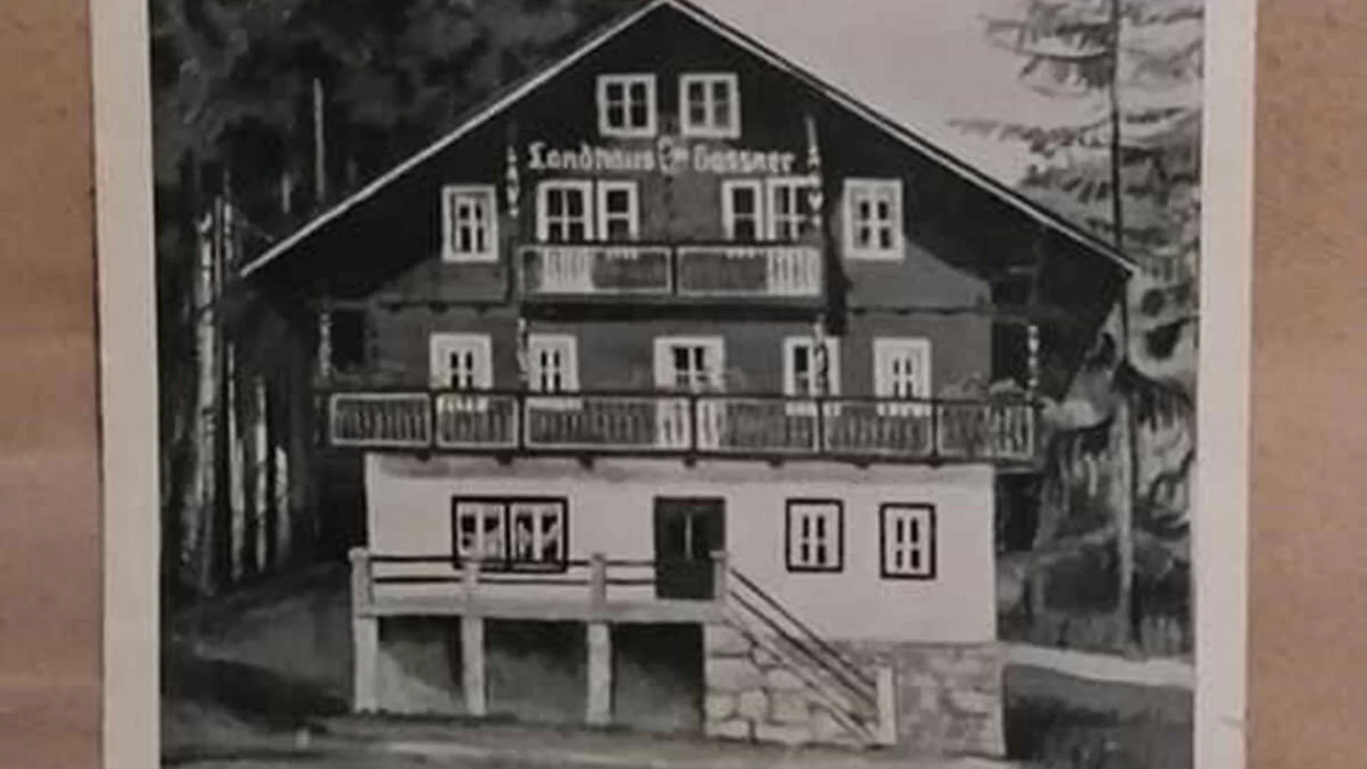 Das Hotel Schwarz-weiß-Foto eines traditionellen Landhauses mit Balustraden und Wald im Hintergrund