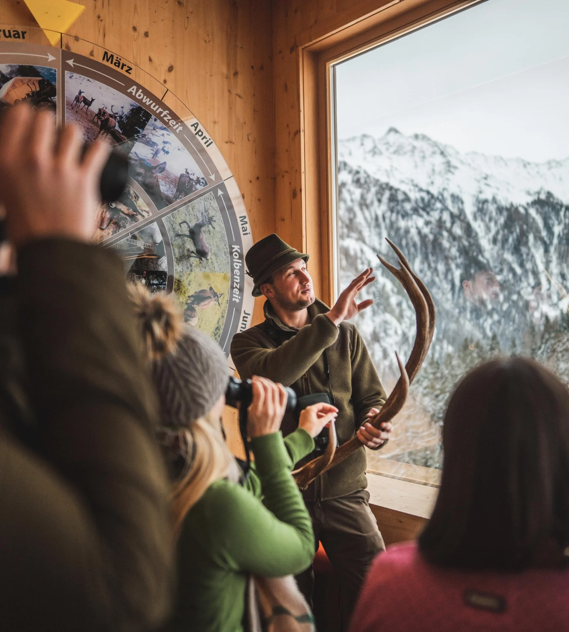 Wanderhotel Jäger erklärt Besuchergruppe Geweih und Wildtierkalender in Berghütte