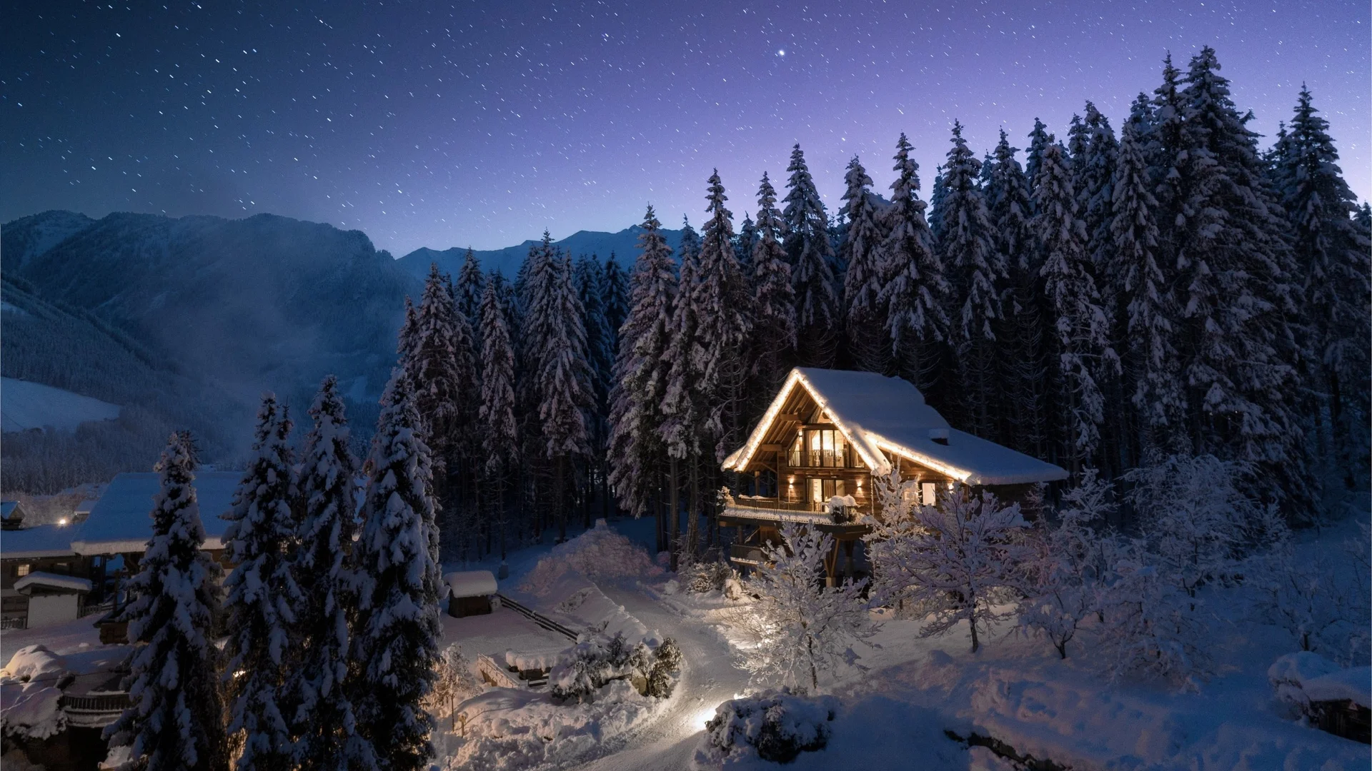 Baumhaus Schneebedecktes Haus bei Nacht mit Lichtern in einem Wald unter einem Sternenhimmel