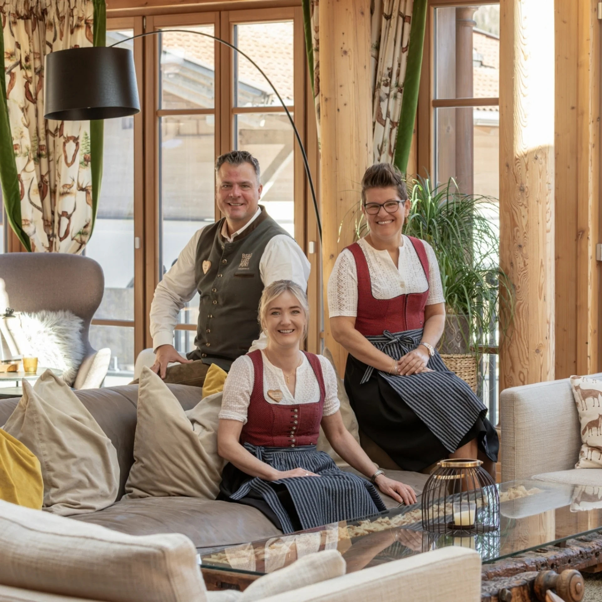 Anfragen Vier Personen in traditioneller Tracht sitzen entspannt am Teich in einem Garten