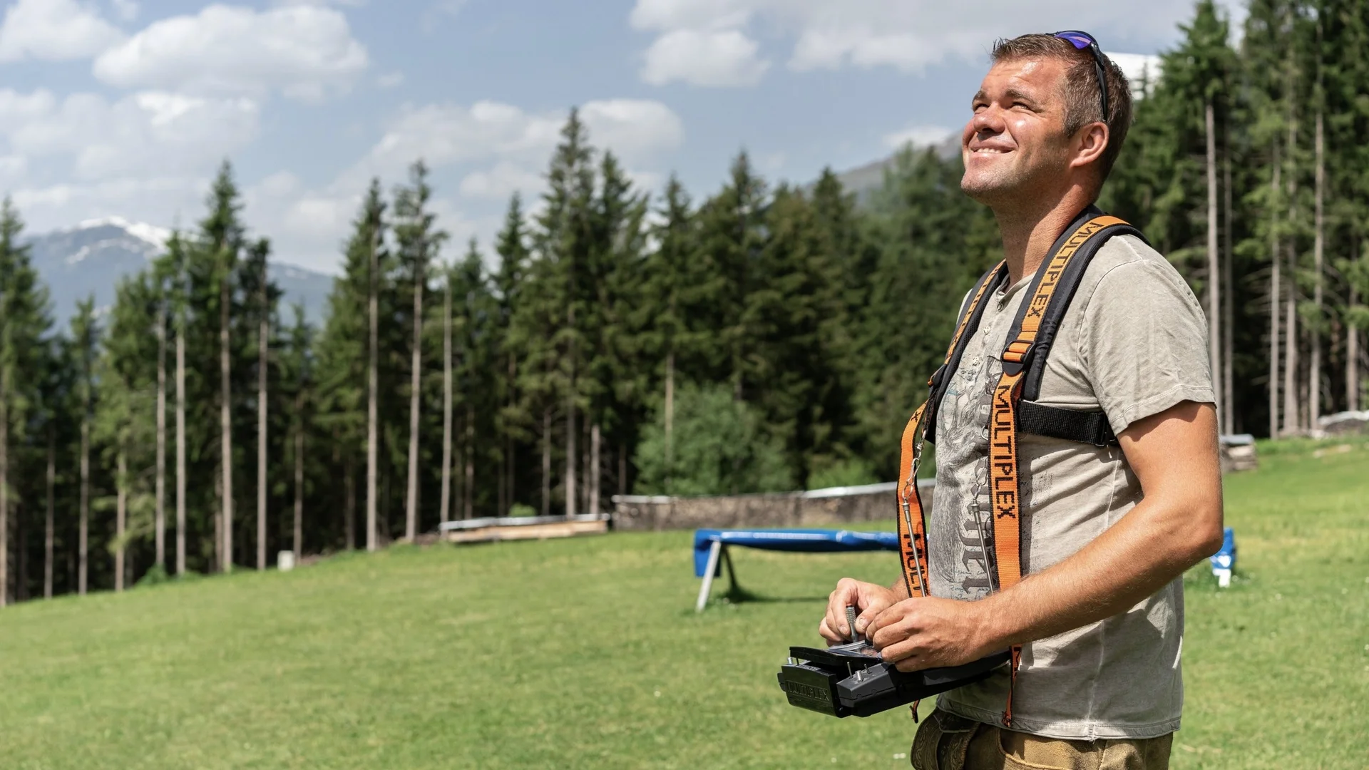 Modell- und Hangfliegen Mann mit Drohnenfernbedienung im Freien vor Wald und Bergen