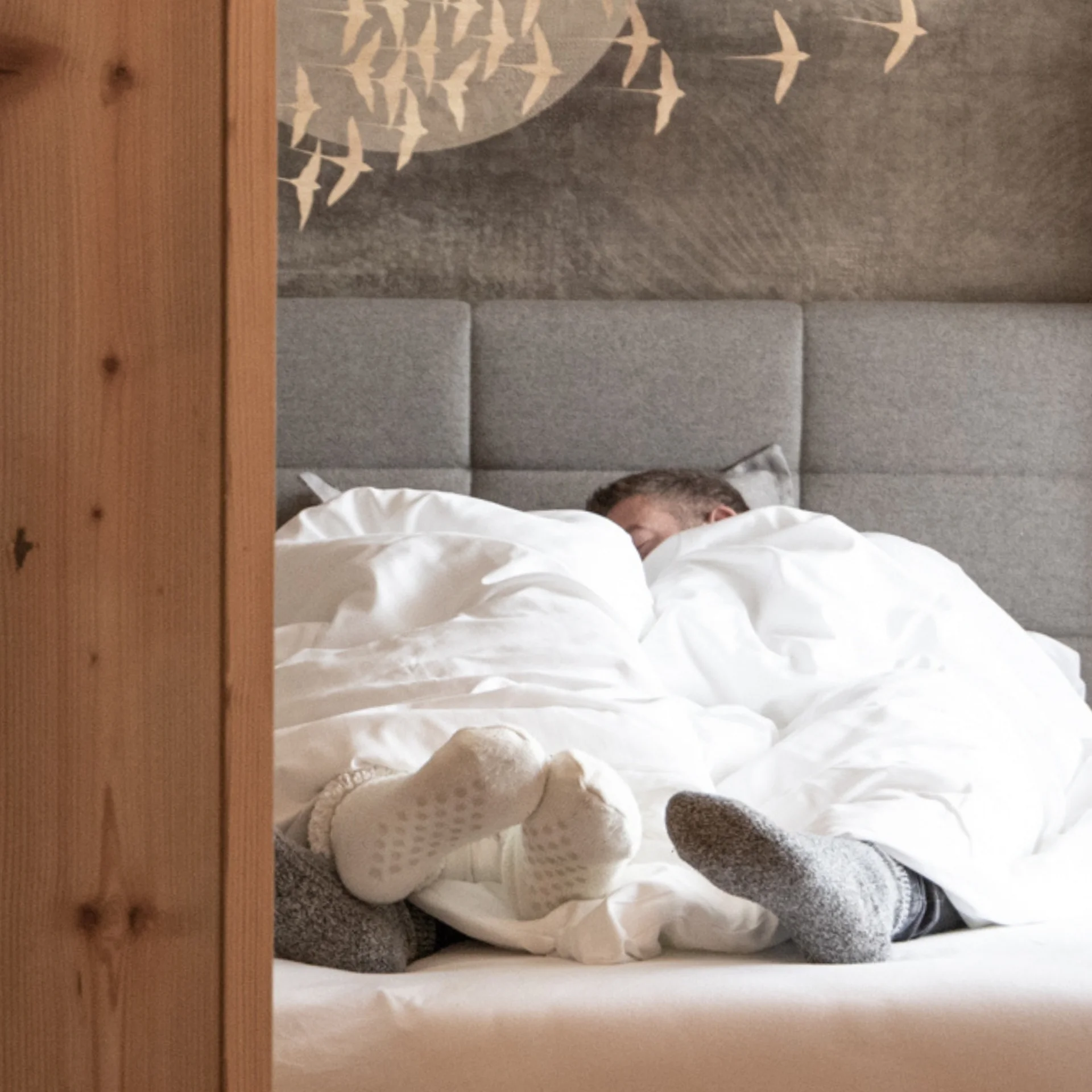 Wohnen Zwei Personen liegen mit Socken im Bett unter weißen Decken in einem Holzraum
