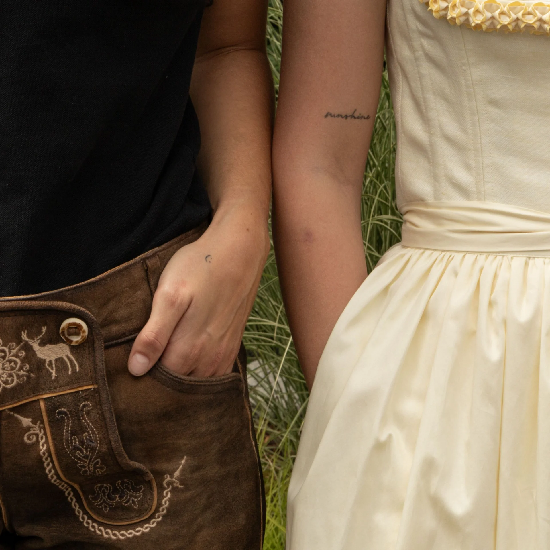 Benefits im Hotel Hände von einem Trachtenpärchen in Lederhose und hellgelbem Dirndl